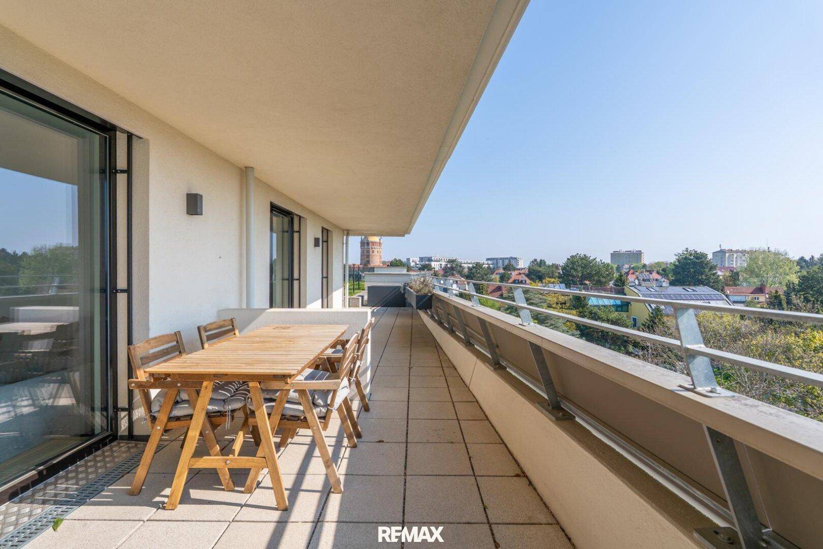 Großer Balkon mit Esstisch und Stühlen, ideal für Mahlzeiten im Freien mit Aussicht.