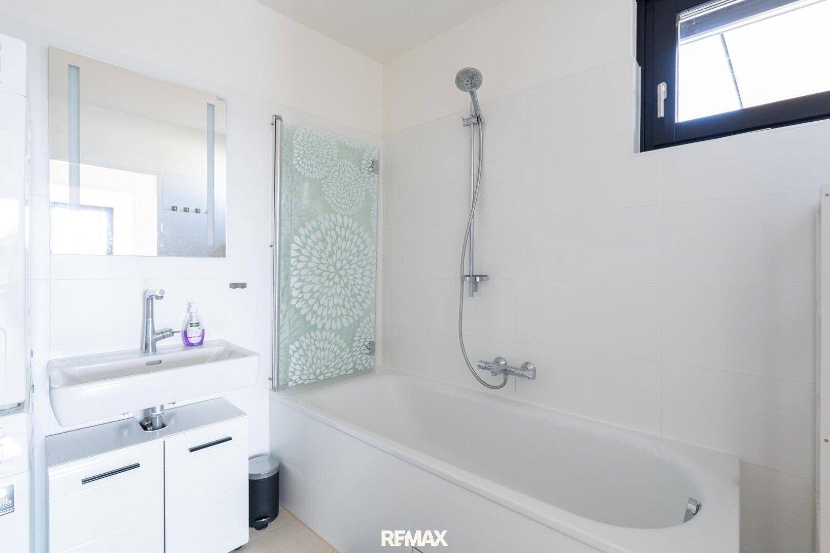 Modernes Badezimmer mit Badewanne, Duschfunktion, Einzelwaschbecken und Fenster.
