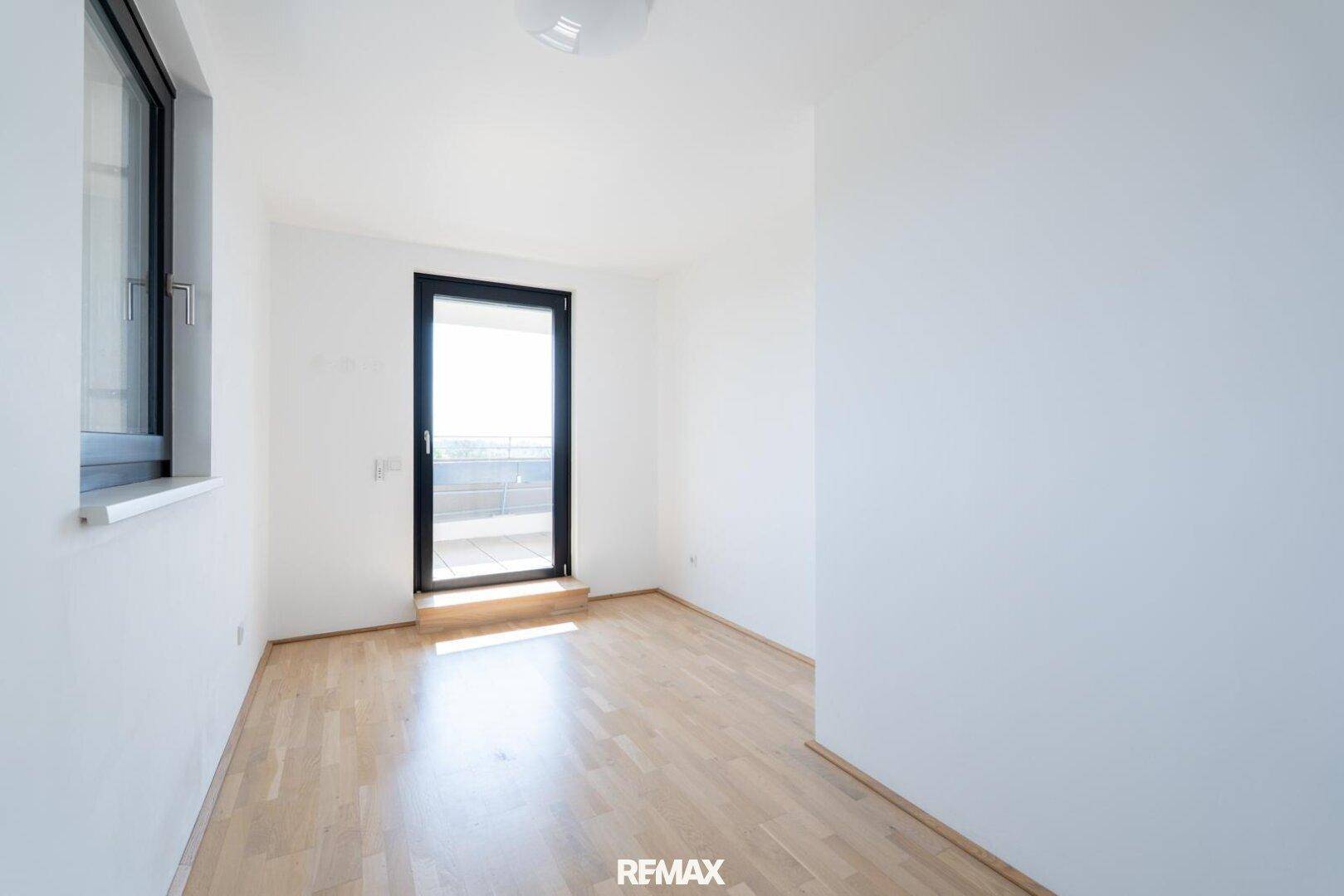 Leeres Zimmer mit Holzboden und Zugang zu einem Außenbereich, ideal als Schlafzimmer.
