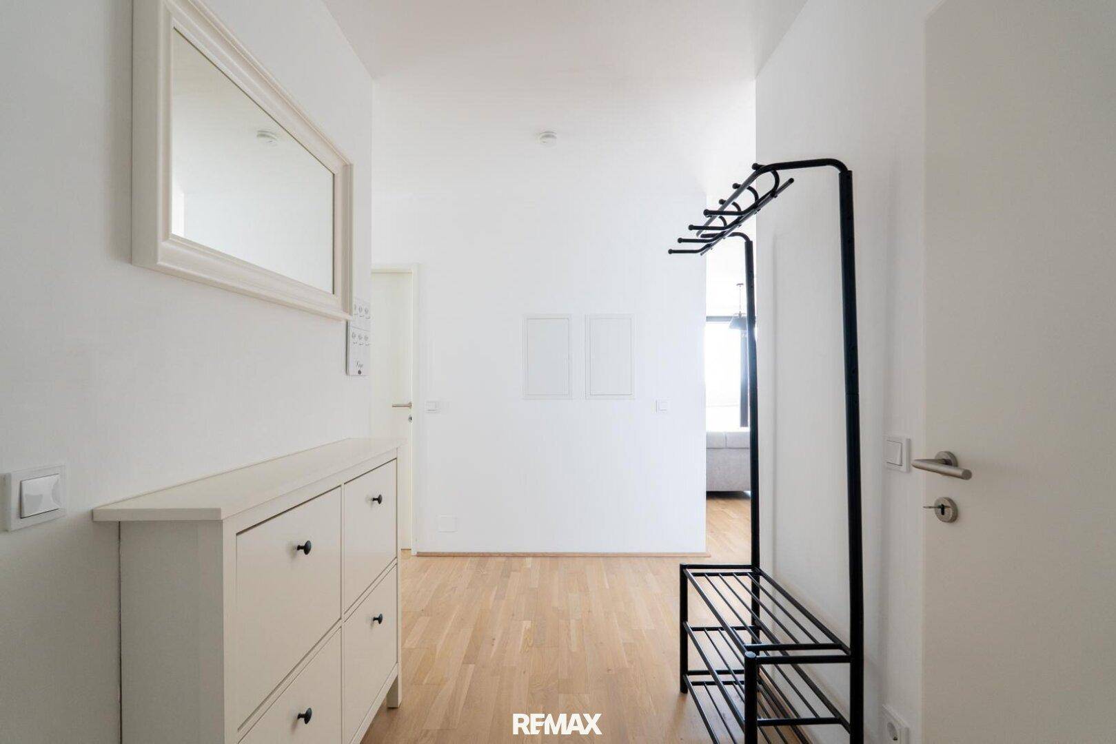 Heller Flur mit Garderobe, Schuhschrank und Holzboden im Eingangsbereich.