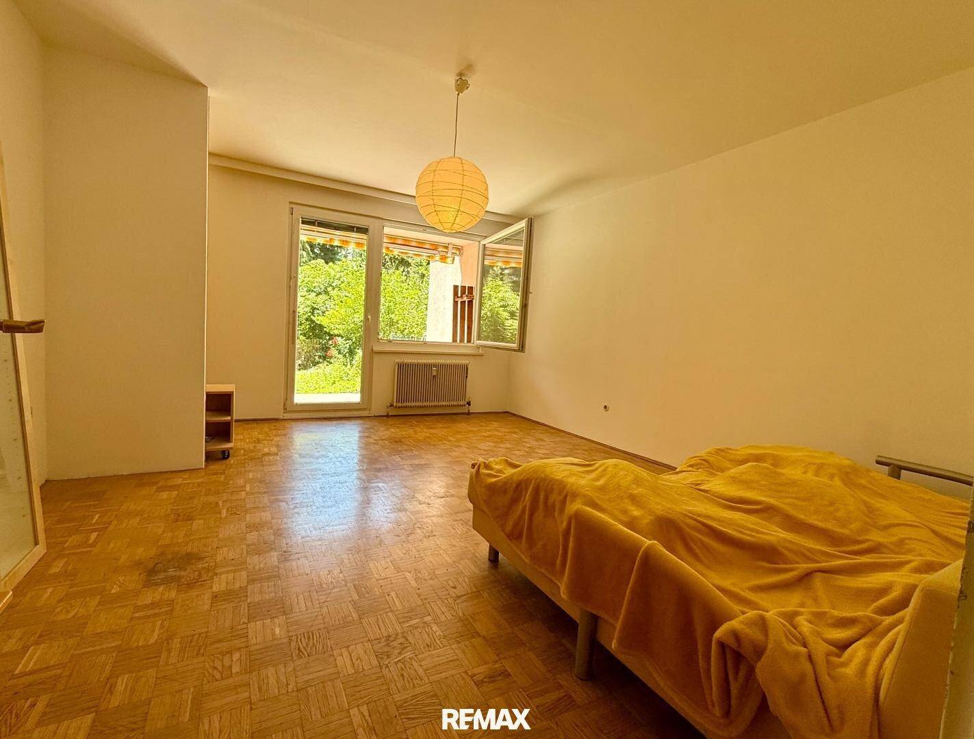 Helles Schlafzimmer mit Parkettboden und Zugang zu einem Außenbereich.