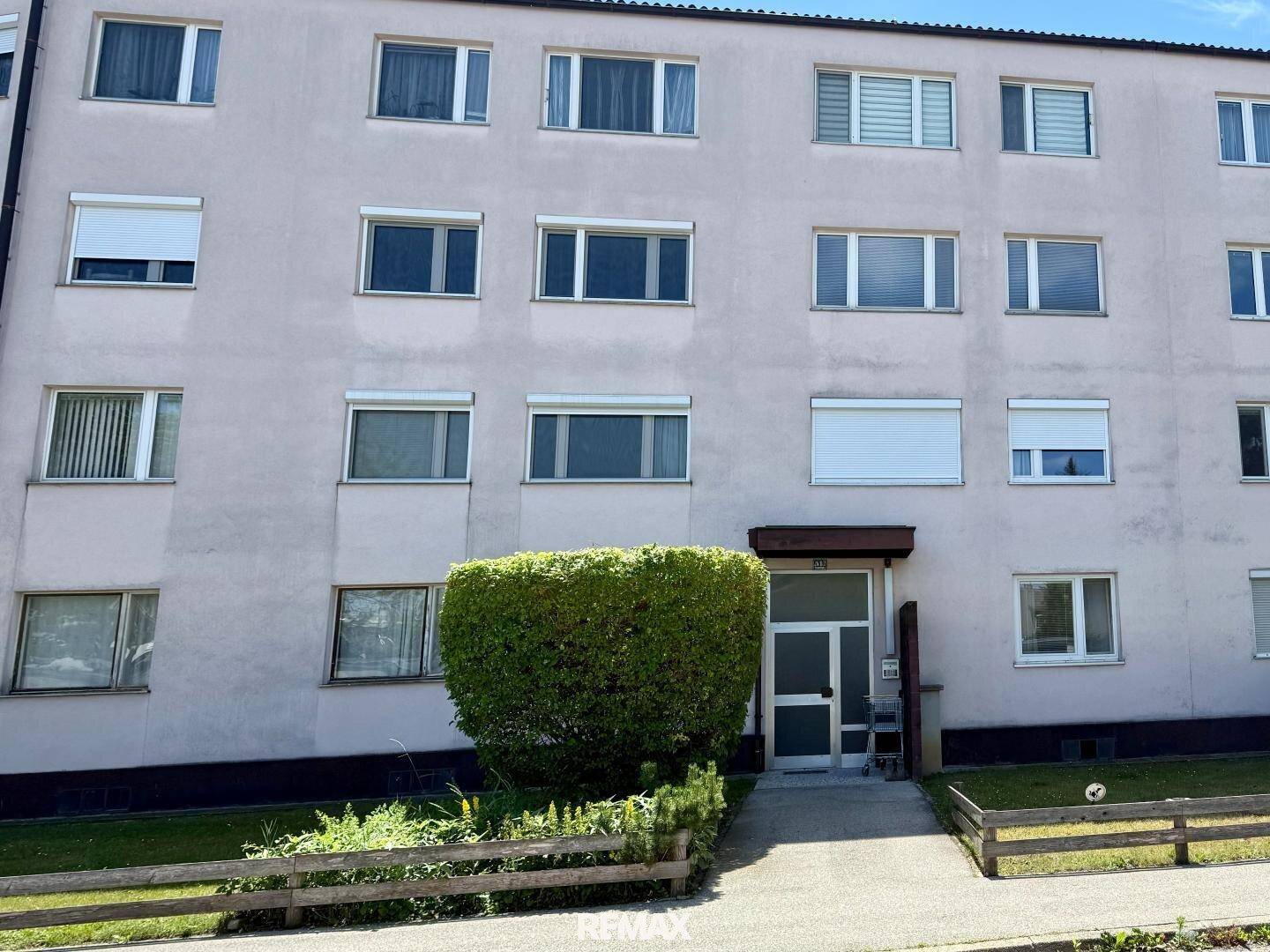 Fassade eines Mehrfamilienhauses mit mehreren Fenstern und Jalousien.