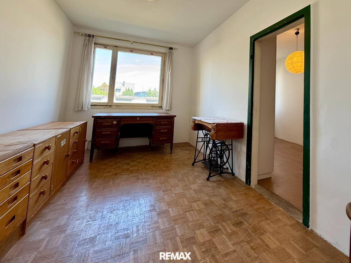 Arbeitszimmer mit Parkettboden, Holzschreibtisch und Fenster für natürliches Licht.