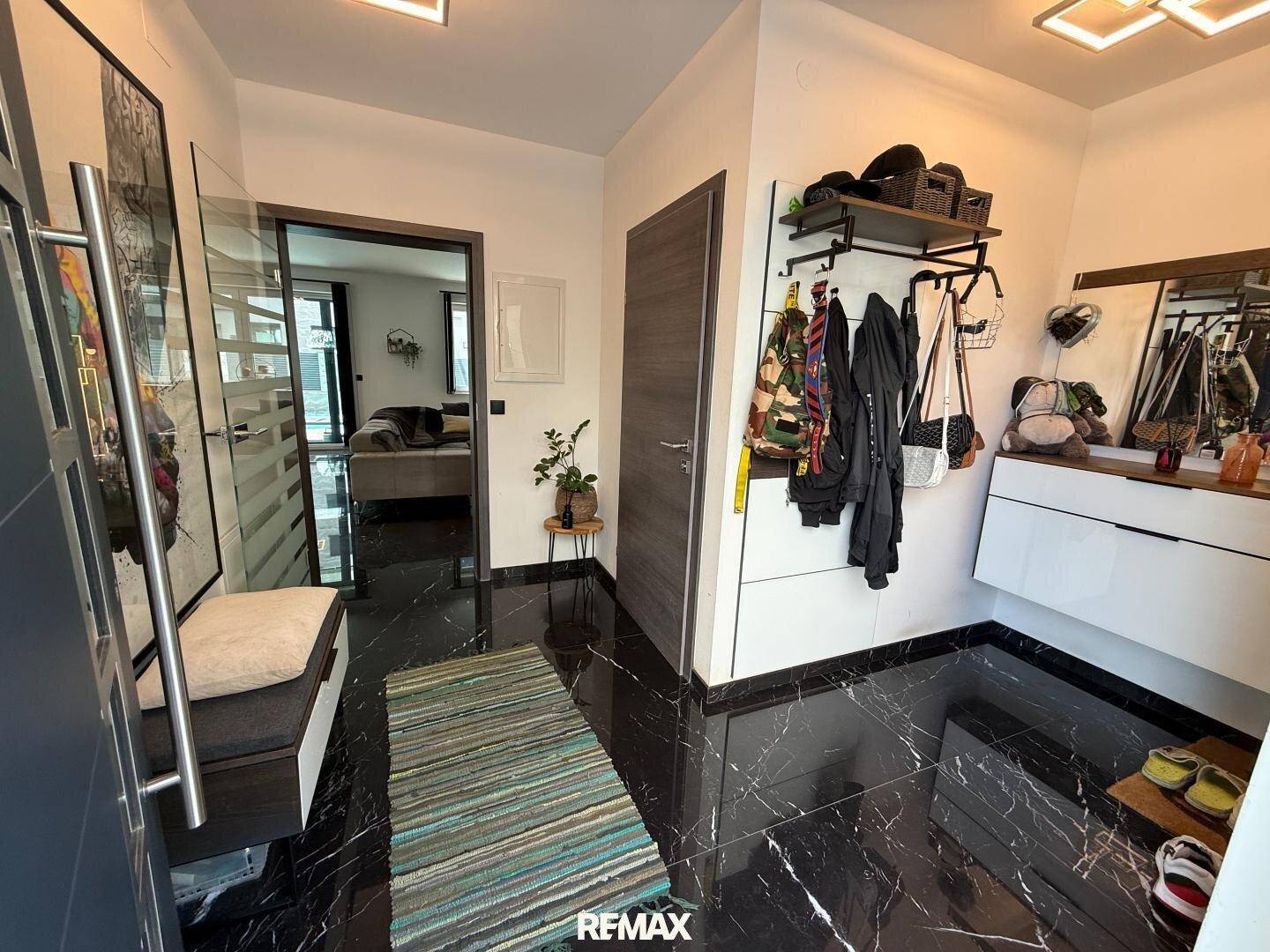 Heller Eingangsbereich mit schwarzem Marmorboden, Garderobe und modernem Design.
