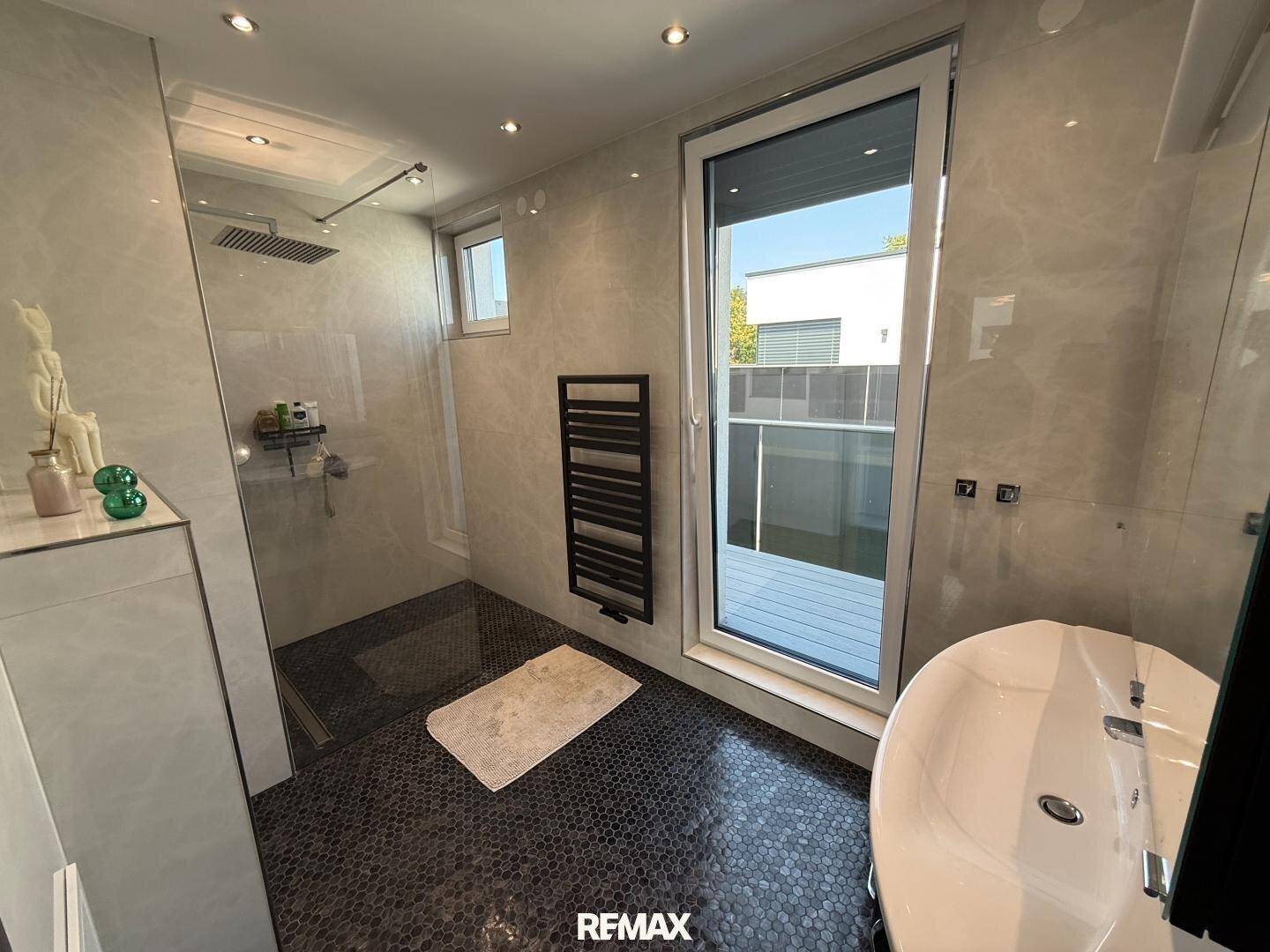 Modernes Badezimmer mit begehbarer Dusche, freistehender Badewanne und dunklem Mosaikboden.