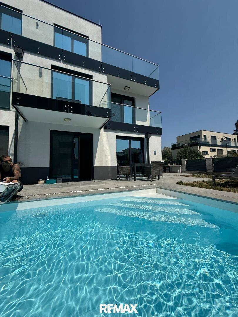 Sonniger Außenbereich mit privatem Pool und moderner Fassade des Wohnhauses.