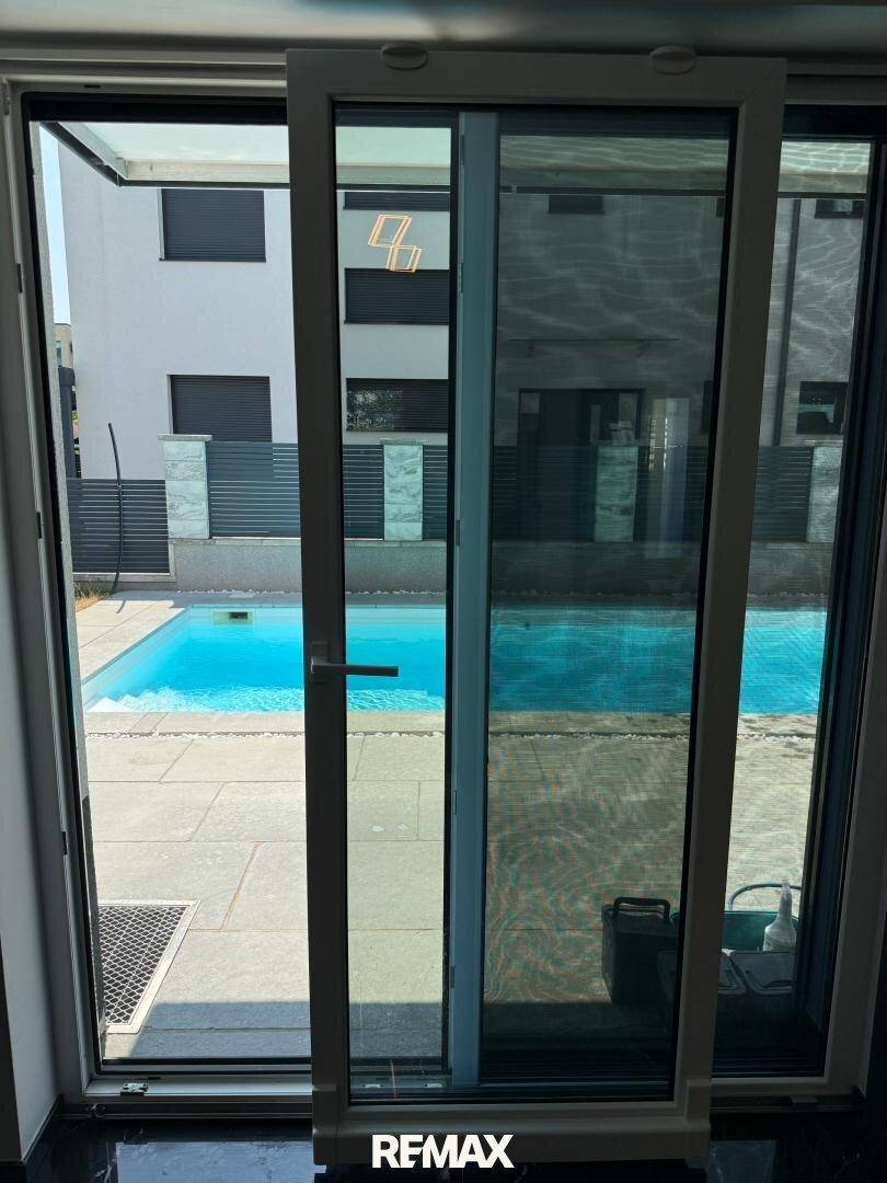 Große Schiebetür bietet direkten Zugang und Blick auf den Außenbereich mit Pool.