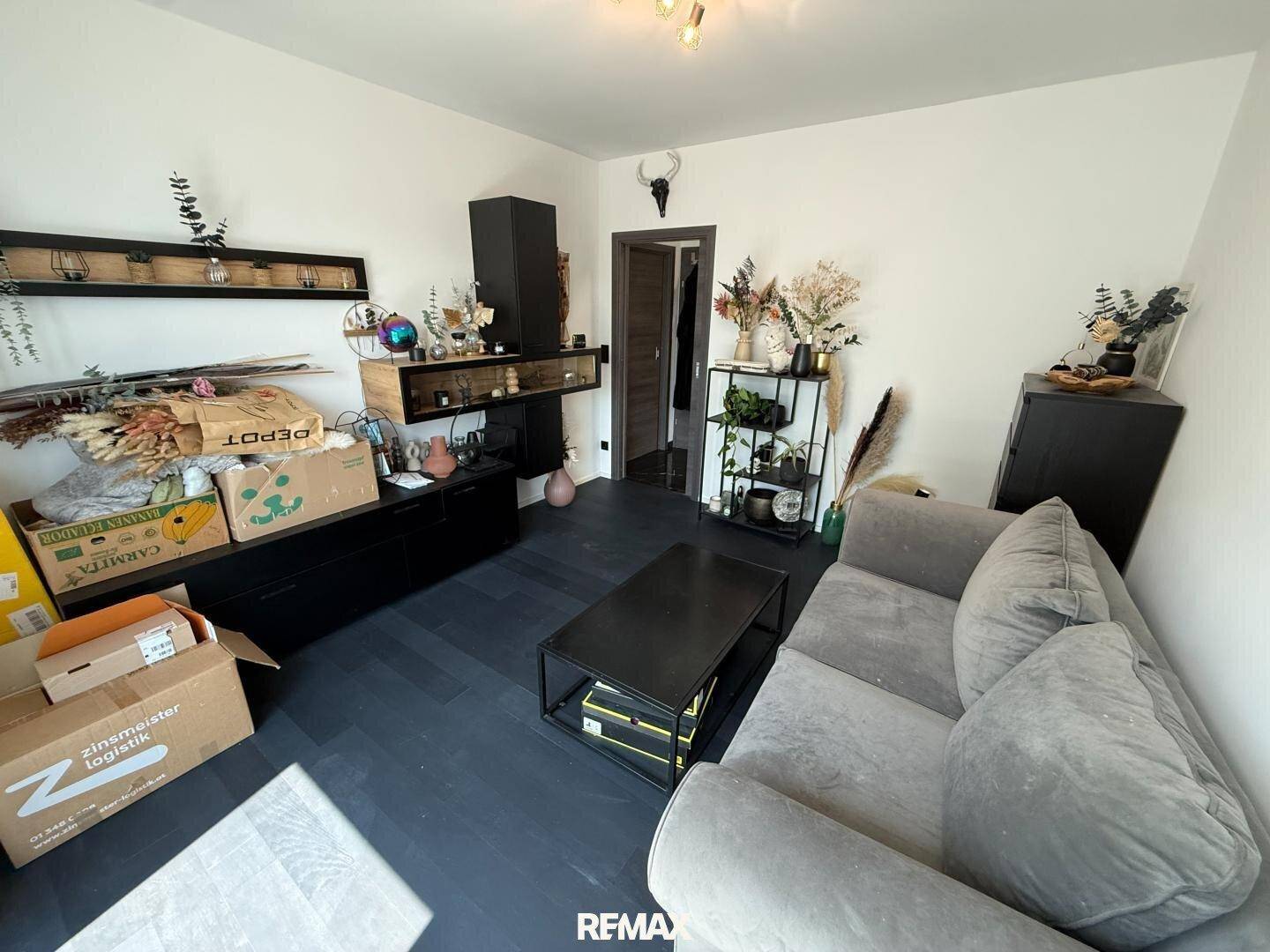 Wohnzimmer mit dunklem Boden, dekorativen Elementen und viel Stauraum in Regalen.