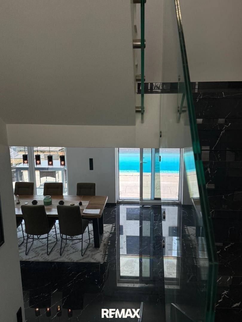 Moderner Essbereich mit großem Holztisch und Blick auf den Außenbereich, verbunden durch eine elegante Treppe.