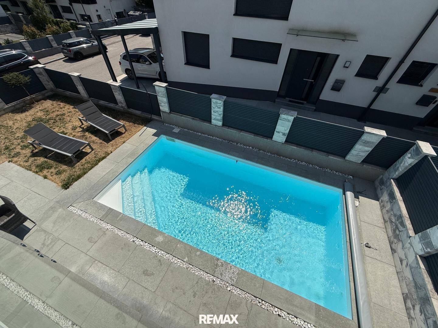 Außenbereich mit privatem Pool, Liegestühlen und kleinem Gartenbereich.