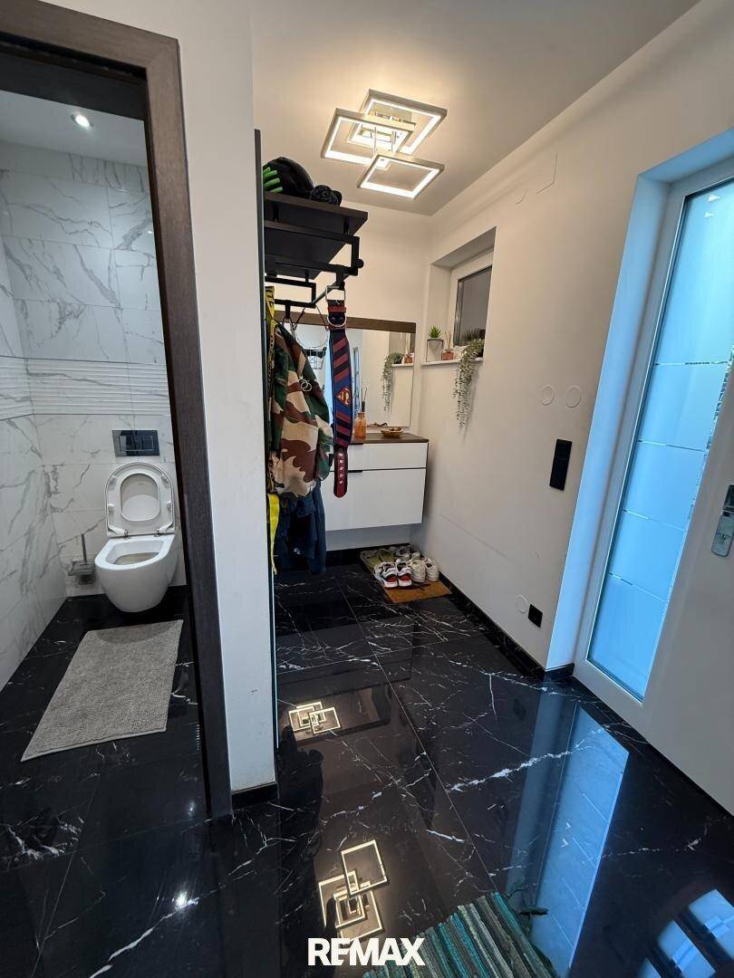 Eingangsbereich mit schwarzem Marmorboden und Blick auf ein modernes Gäste-WC.