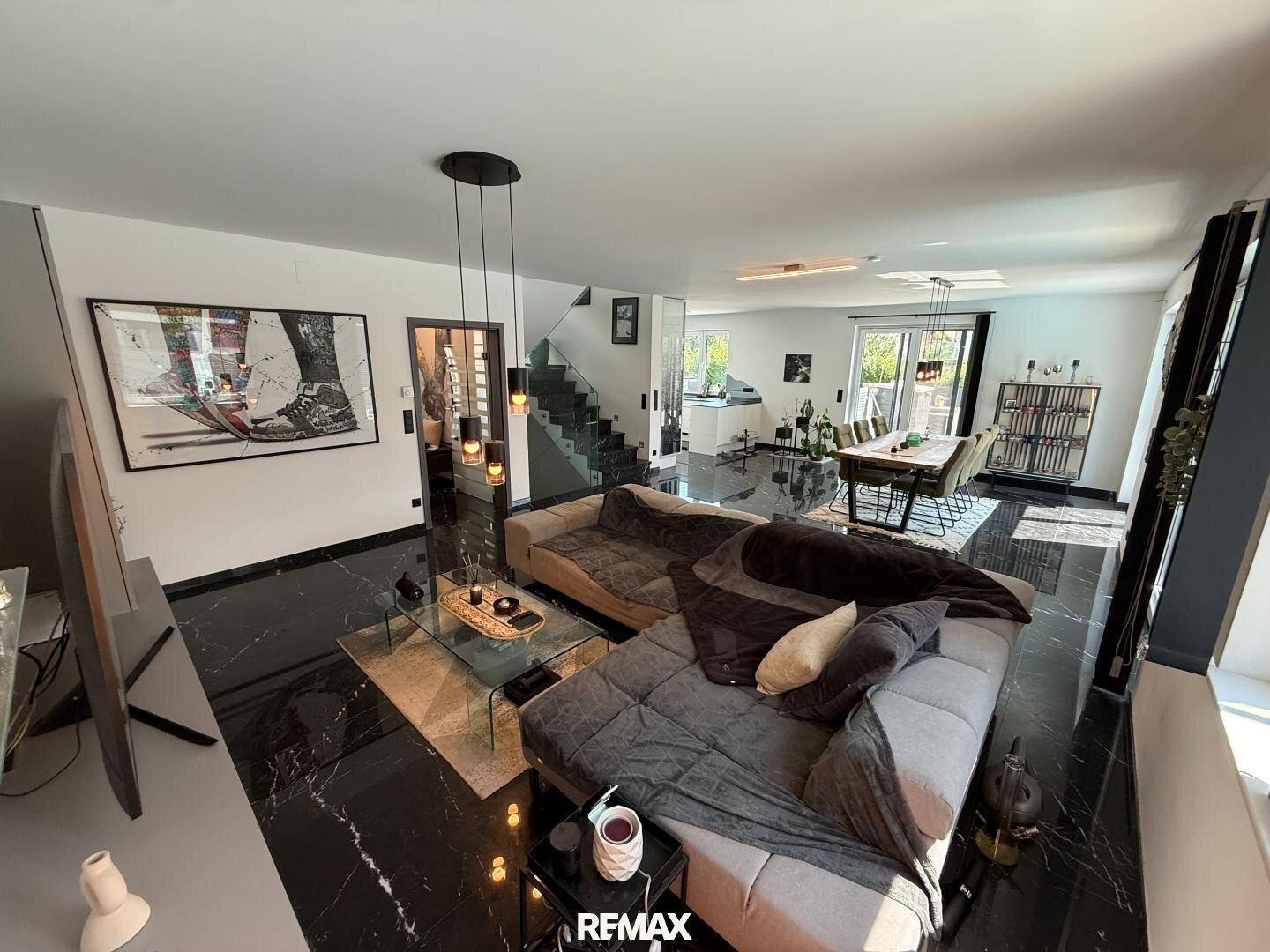 Gemütlicher Wohnbereich mit großem Sofa, modernem Design und glänzendem schwarzen Marmorboden.