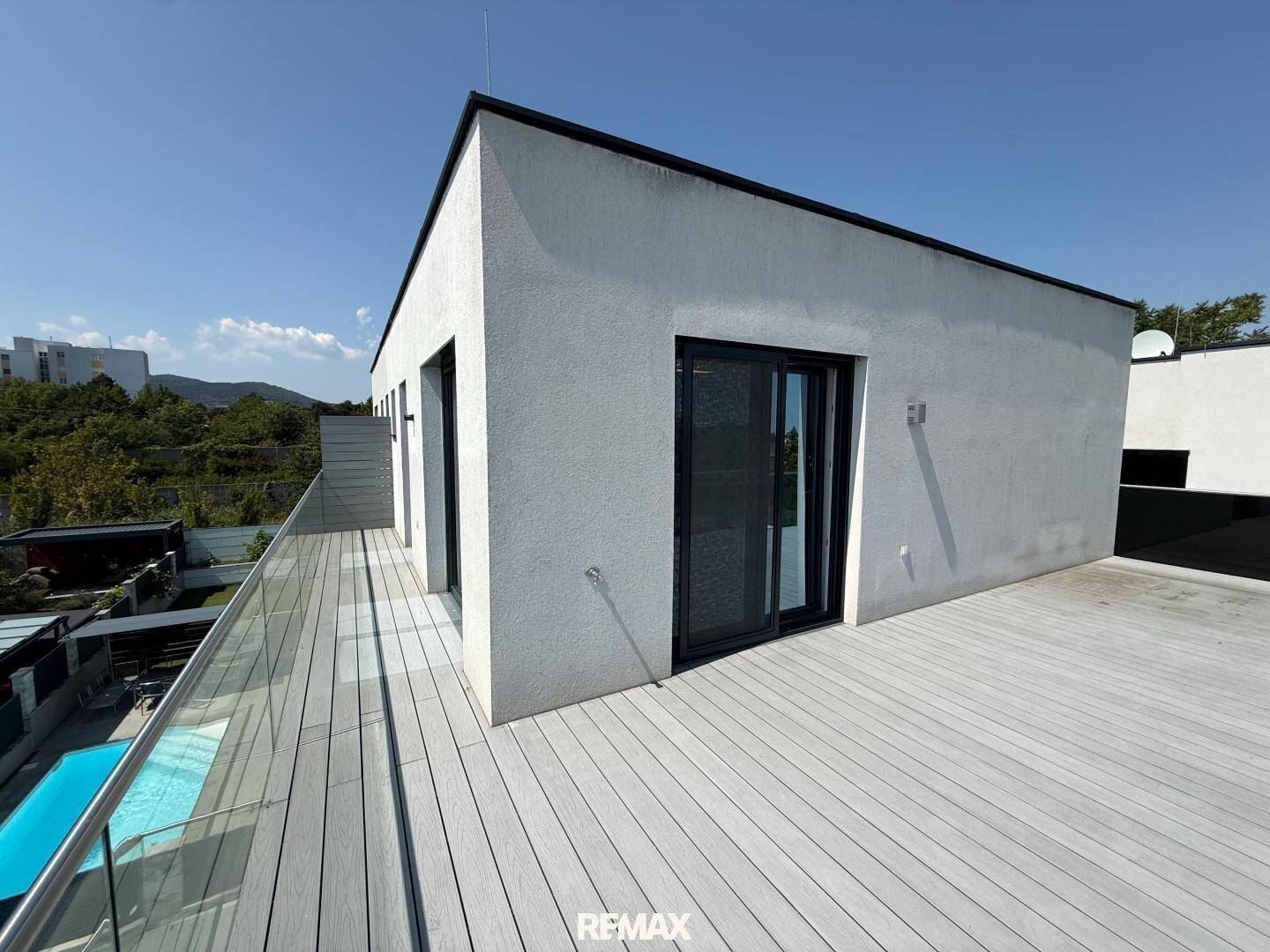 Große Dachterrasse mit Holzdeck und moderner Glasbrüstung, ideal zum Entspannen.