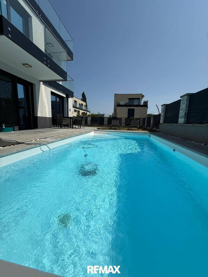 Außenansicht des modernen Hauses mit erfrischendem Pool und sonniger Terrasse.