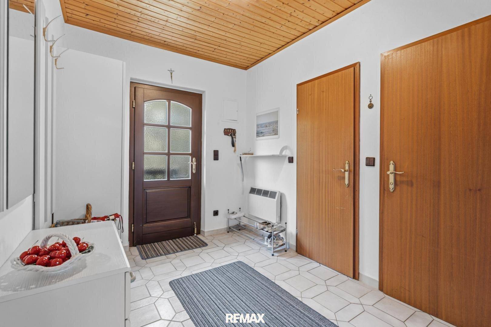 Heller Flur mit Holzdecke, Fliesenboden und Garderobe im Eingangsbereich.