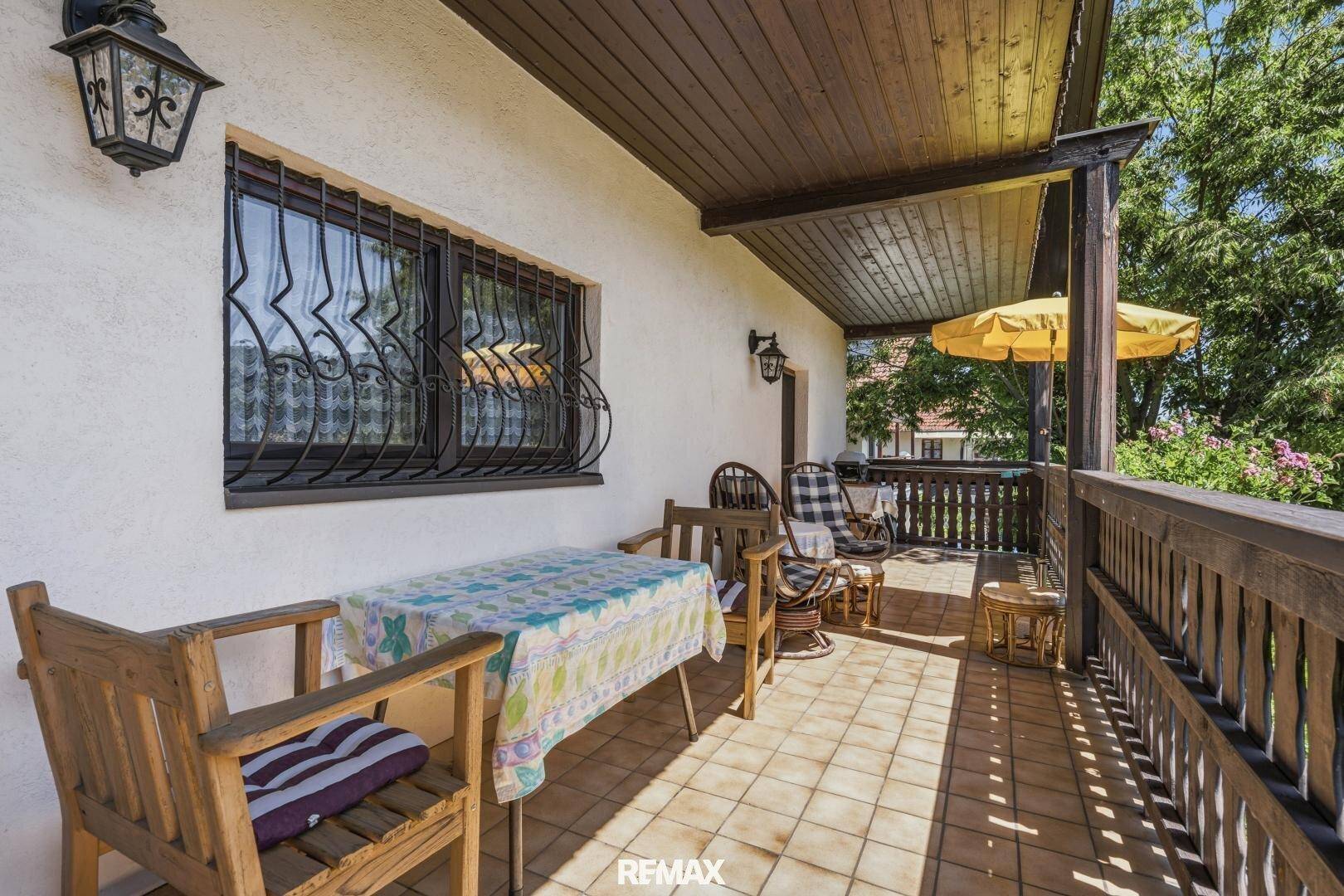 Überdachter Balkon mit Sitzgelegenheiten und Blick auf die grüne Umgebung.
