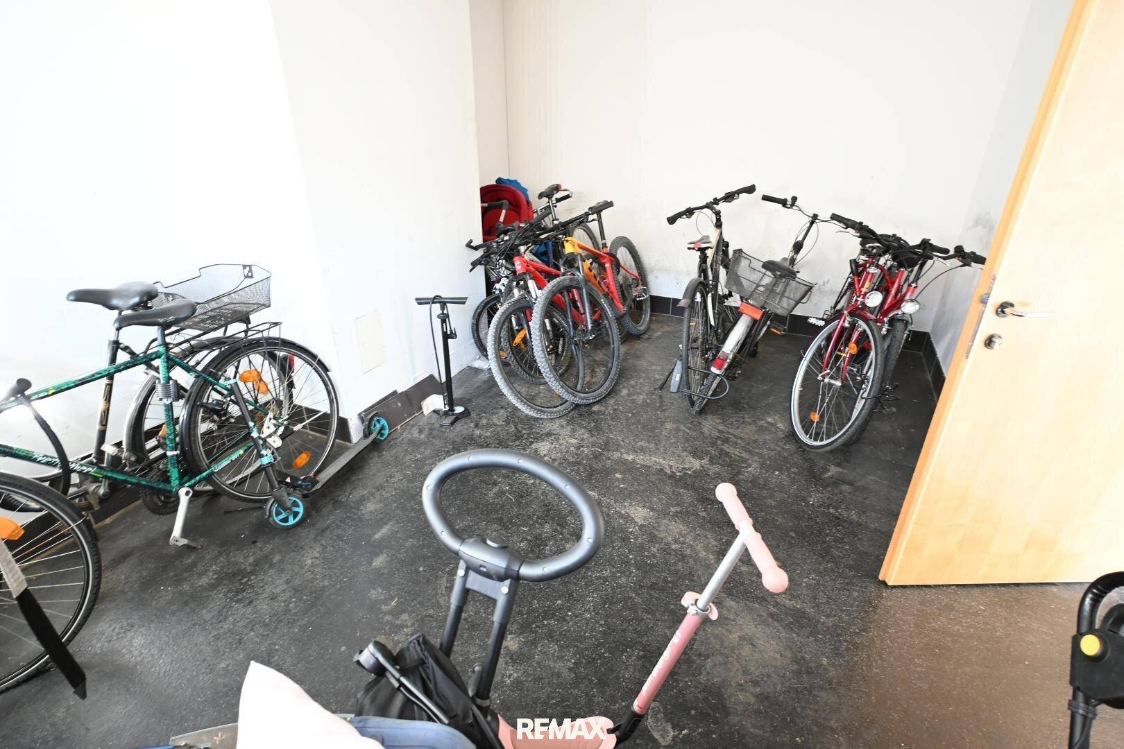 Fahrradraum mit mehreren Fahrrädern und einem Roller, ideal zur sicheren Aufbewahrung.