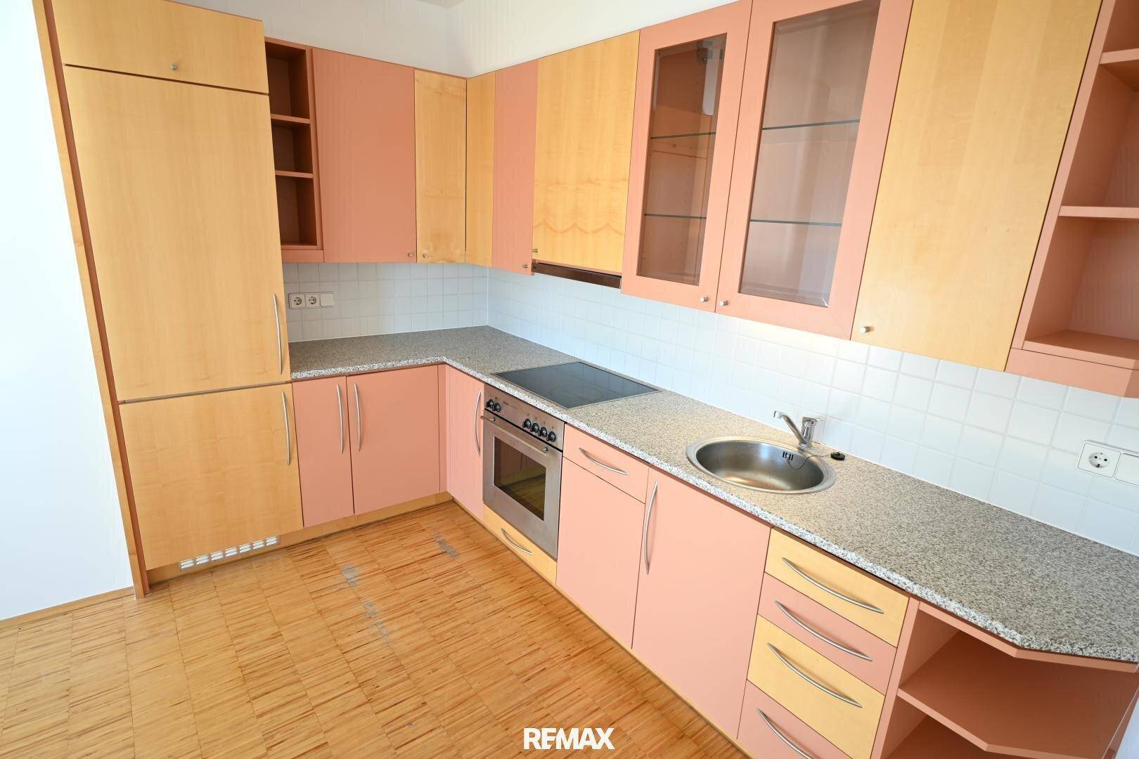 Detailansicht der Küchenzeile mit hellen Holz- und Rosatönen, Spüle, Kochfeld und integriertem Backofen.