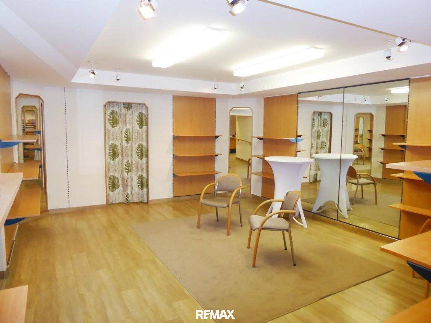 Geräumiger Verkaufsraum mit Holzfußboden, Spiegelfront und flexiblen Regalsystemen.