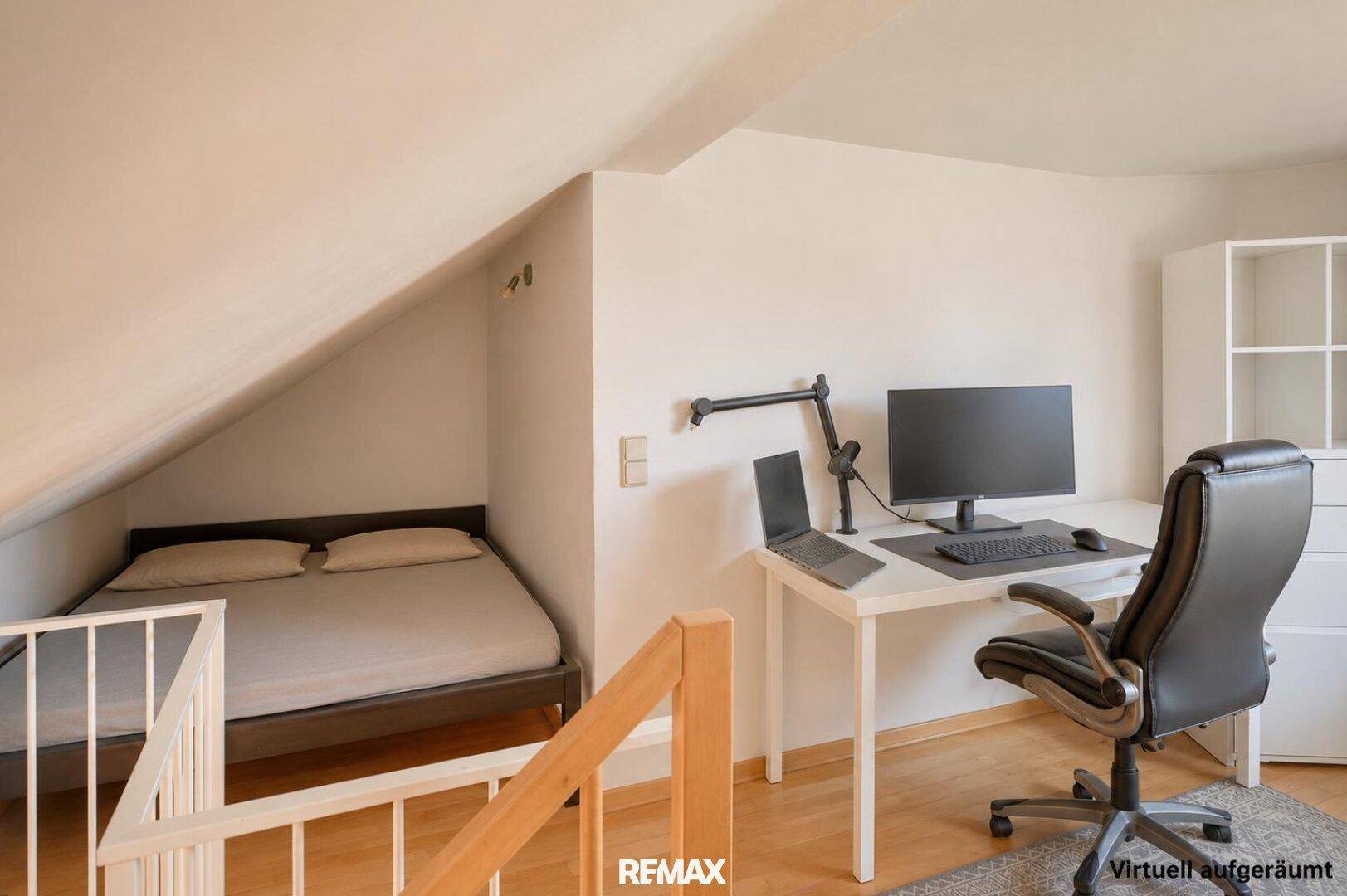 Schlafbereich im Dachgeschoss mit Bett unter der Dachschräge und angrenzendem Arbeitsplatz.