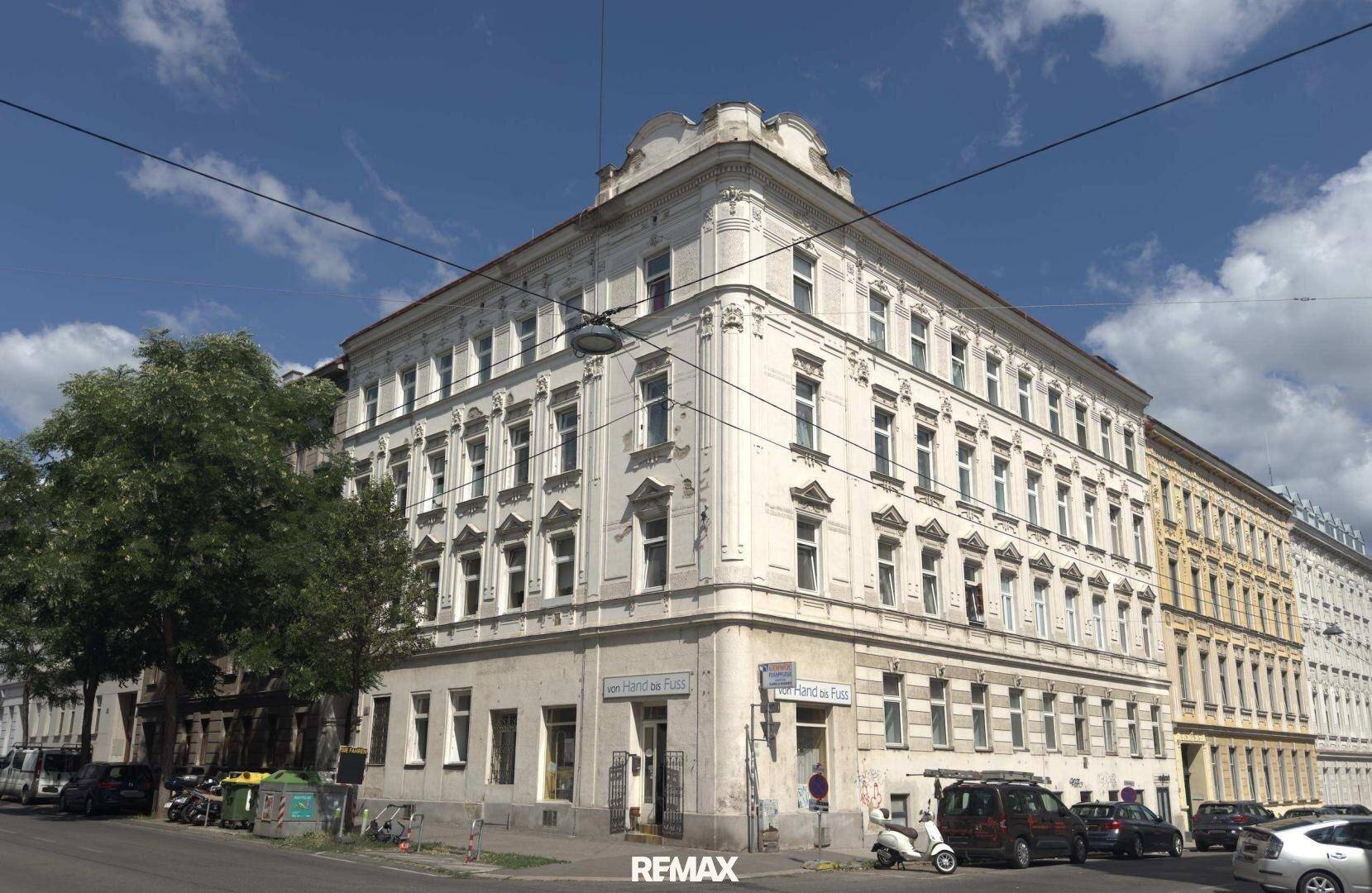 Historisches Eckgebäude mit klassischer Architektur und vielen Fenstern an einer städtischen Straße.