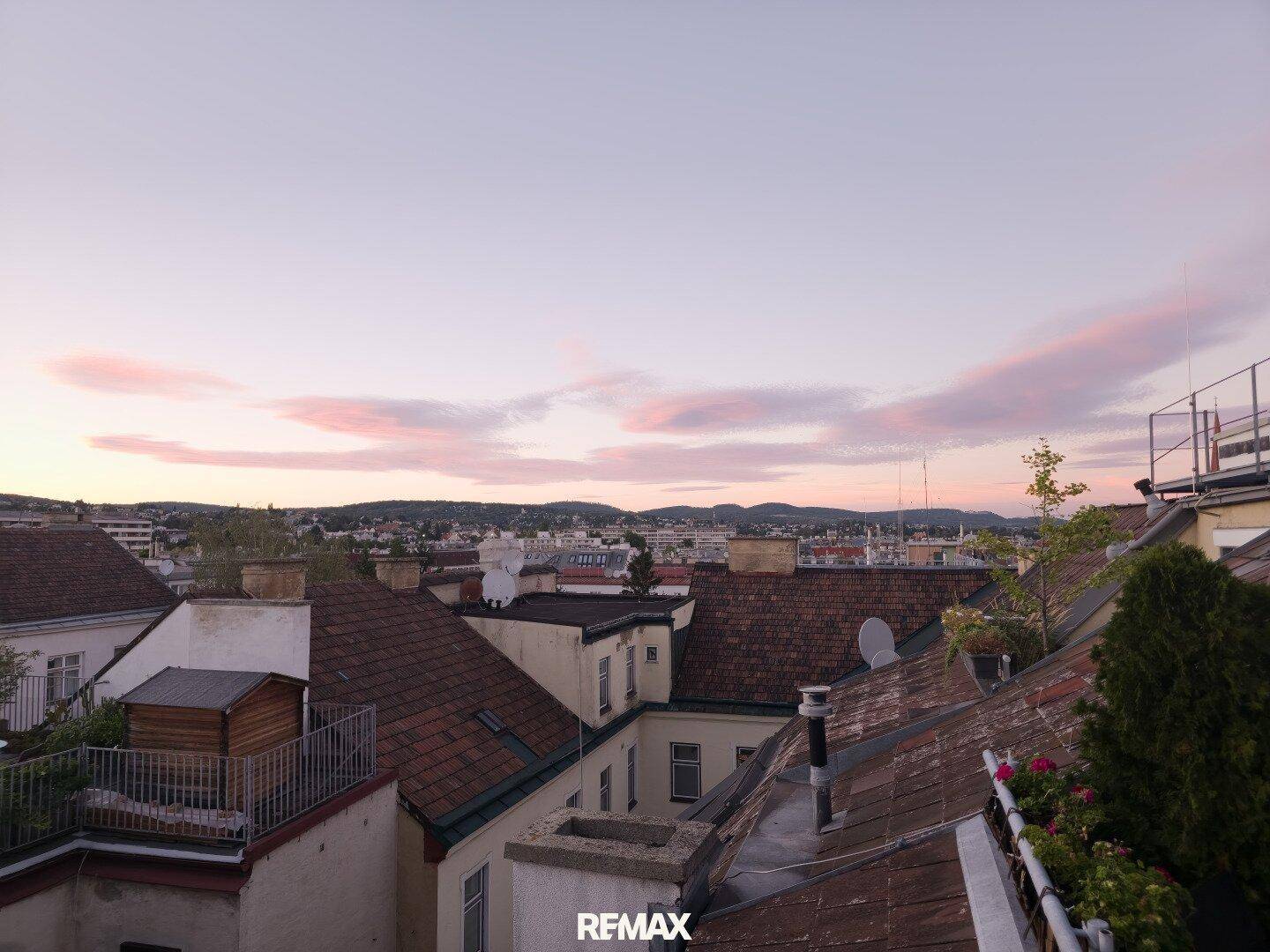 Abendlicher Blick über die Dächer der Stadt mit einem malerischen Sonnenuntergangshimmel.
