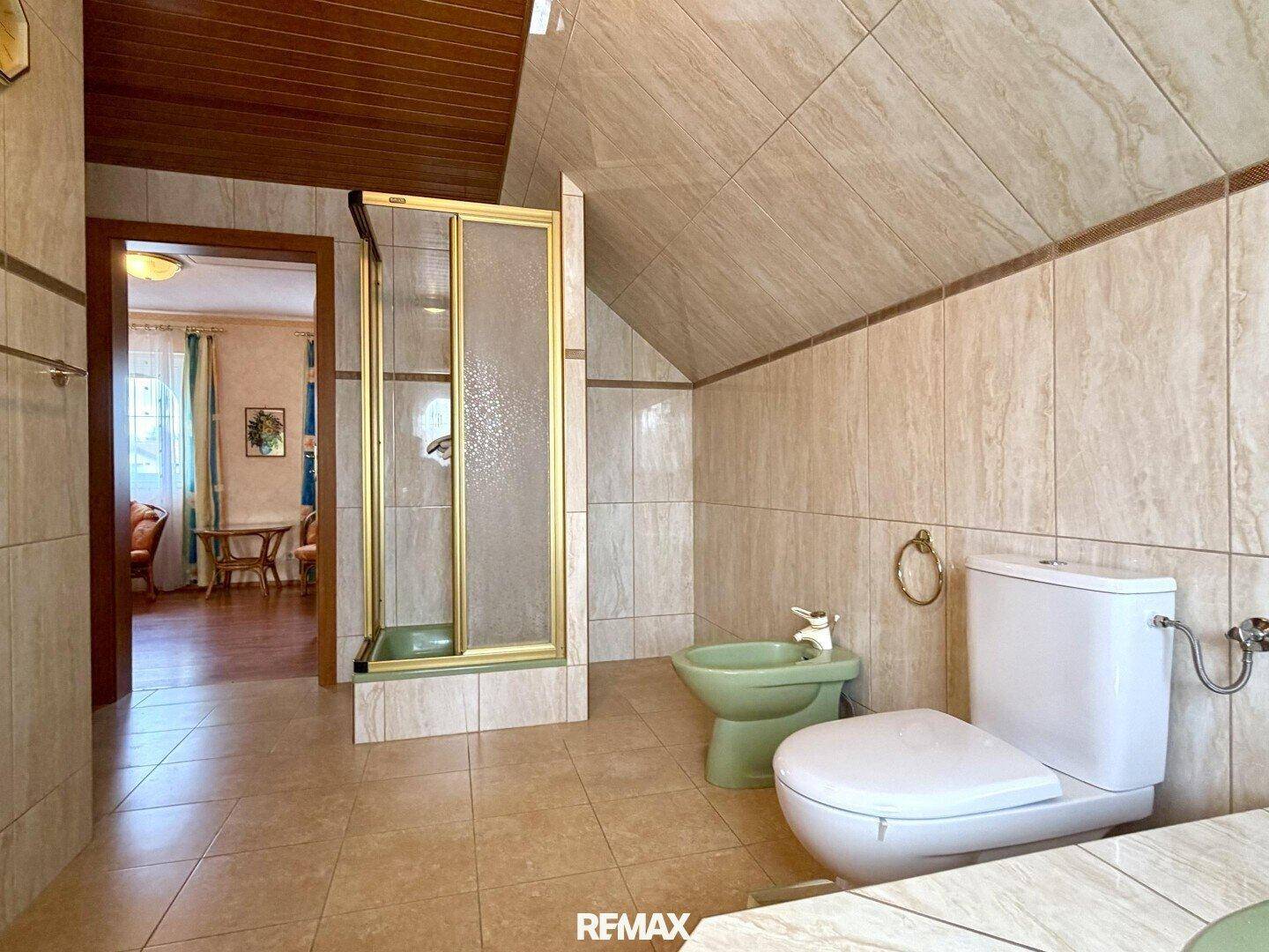 Badezimmer mit Dusche, WC und Bidet, direktem Zugang zu einem weiteren Raum.