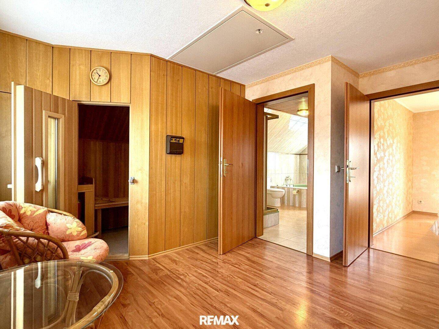 Flur mit Holzvertäfelung, Zugang zur Sauna und weiteren Zimmern, mit hellem Holzboden.