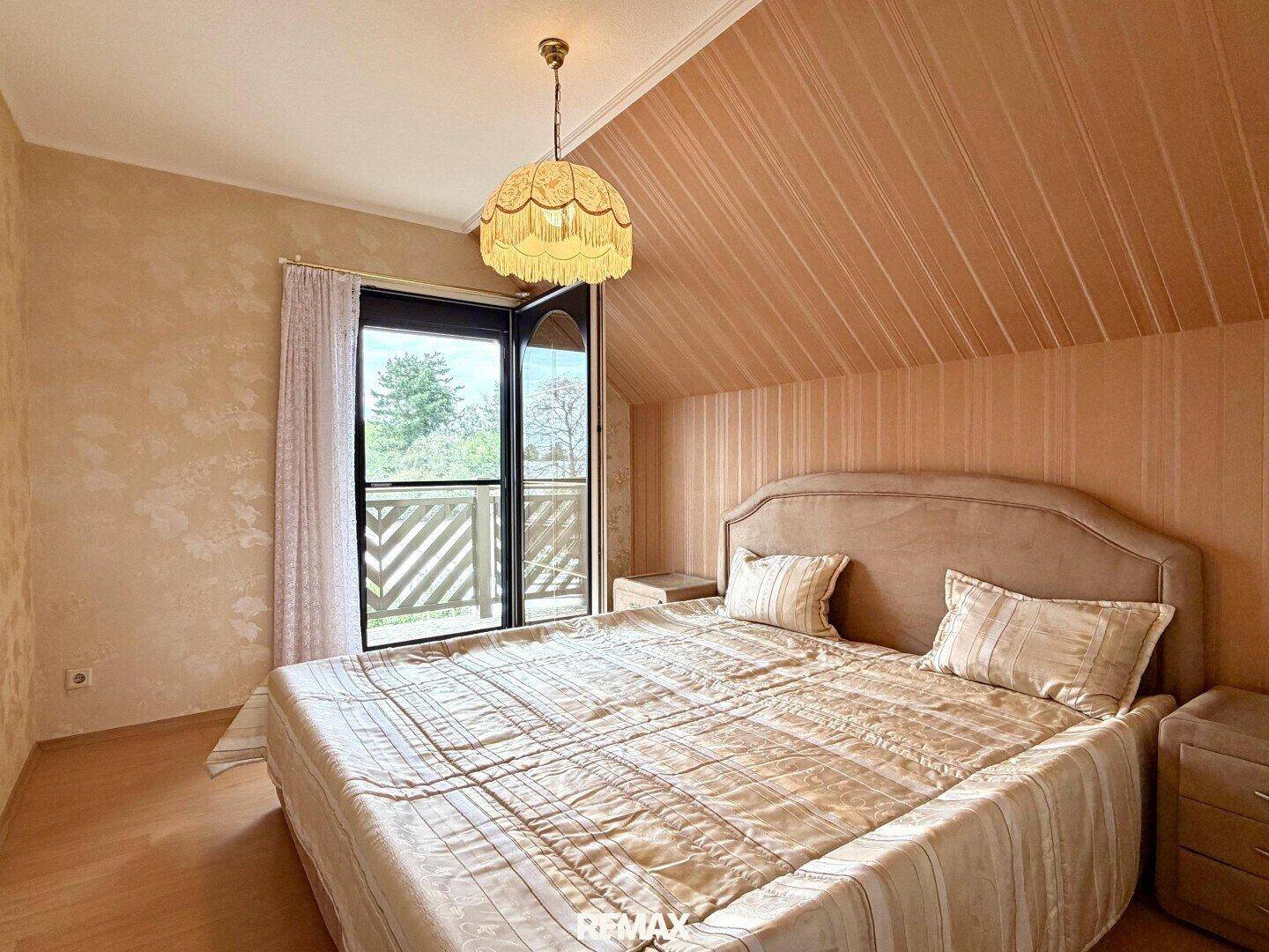 Gemütliches Schlafzimmer mit Doppelbett, Dachschräge und Zugang zum Balkon für frische Luft.