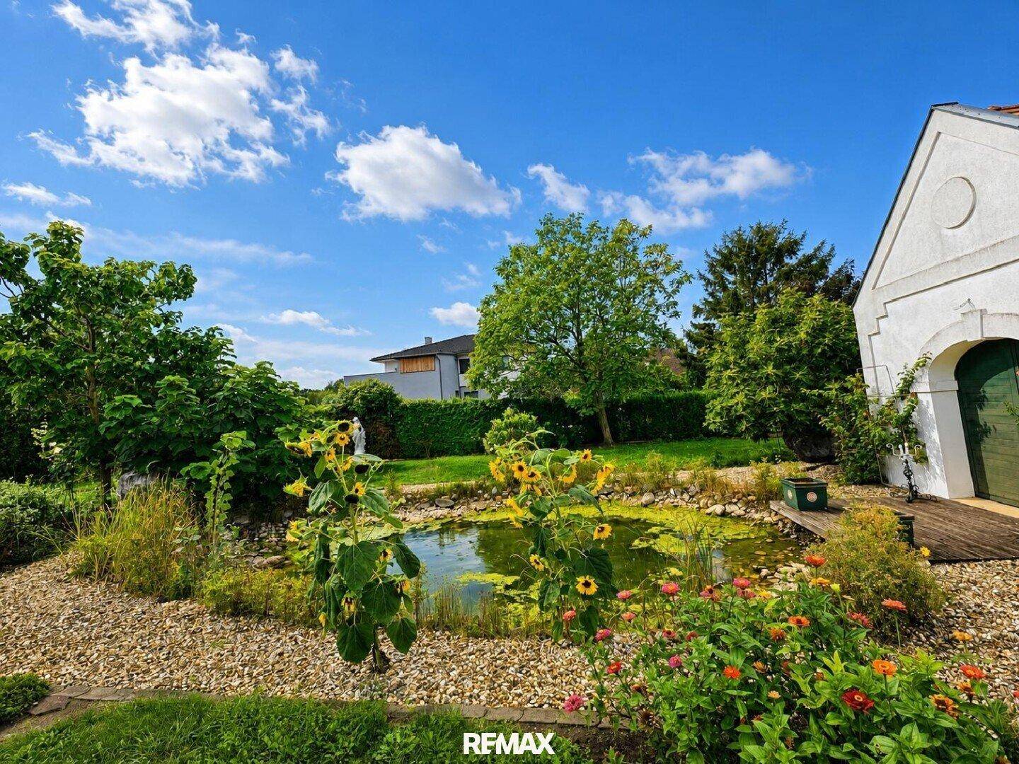 Naturnaher Gartenteich umgeben von üppiger Vegetation und blühenden Sonnenblumen.