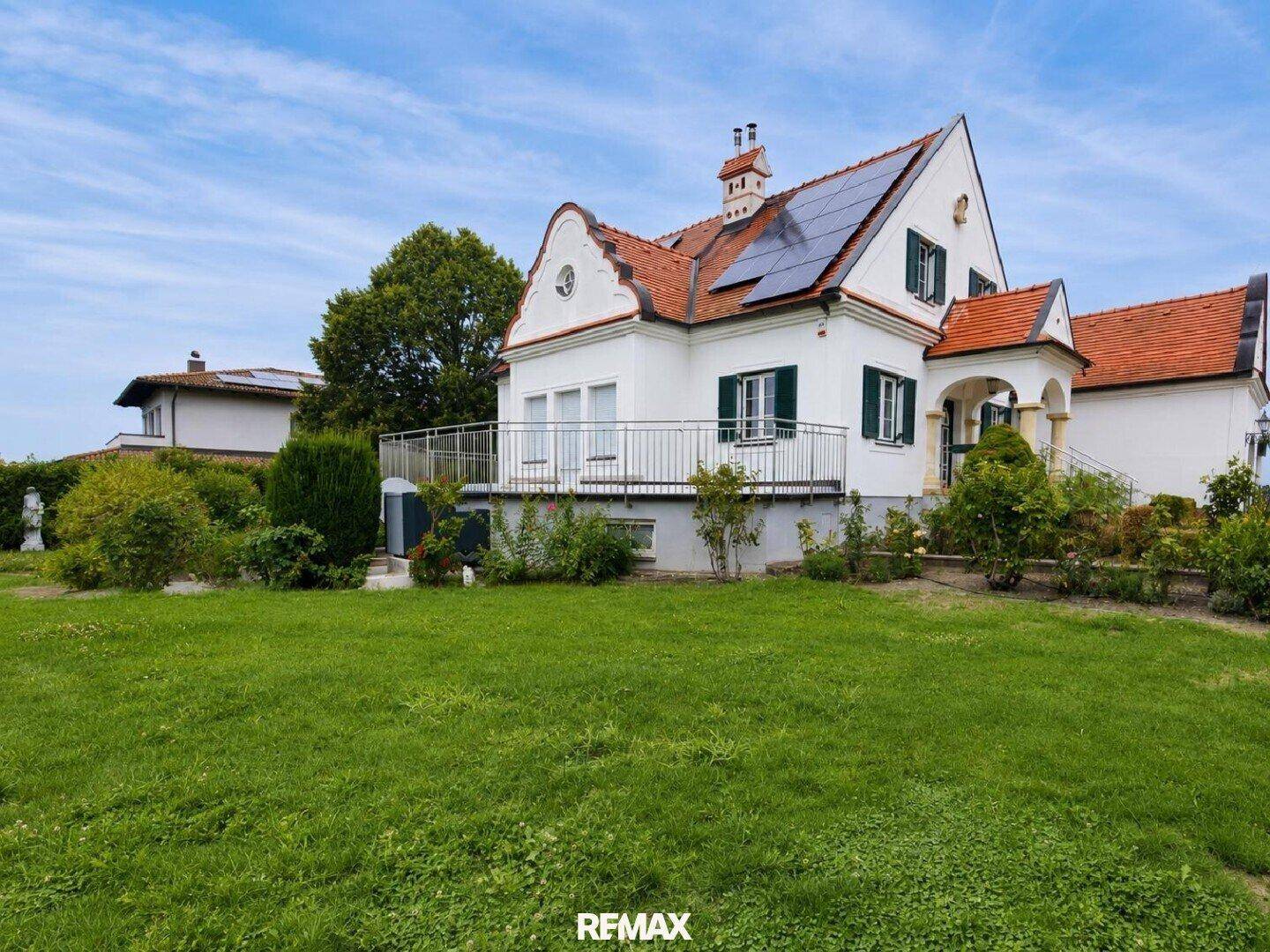 Seitenansicht des Hauses vom Garten aus mit Terrasse und Blick ins Grüne.
