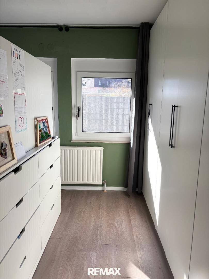 Raum mit Einbauschränken, Fenster und Laminatboden, ideal als Ankleidezimmer.
