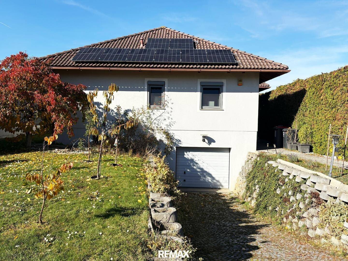 Rückseite des Hauses mit integrierter Garage und Photovoltaikanlage auf dem Dach.