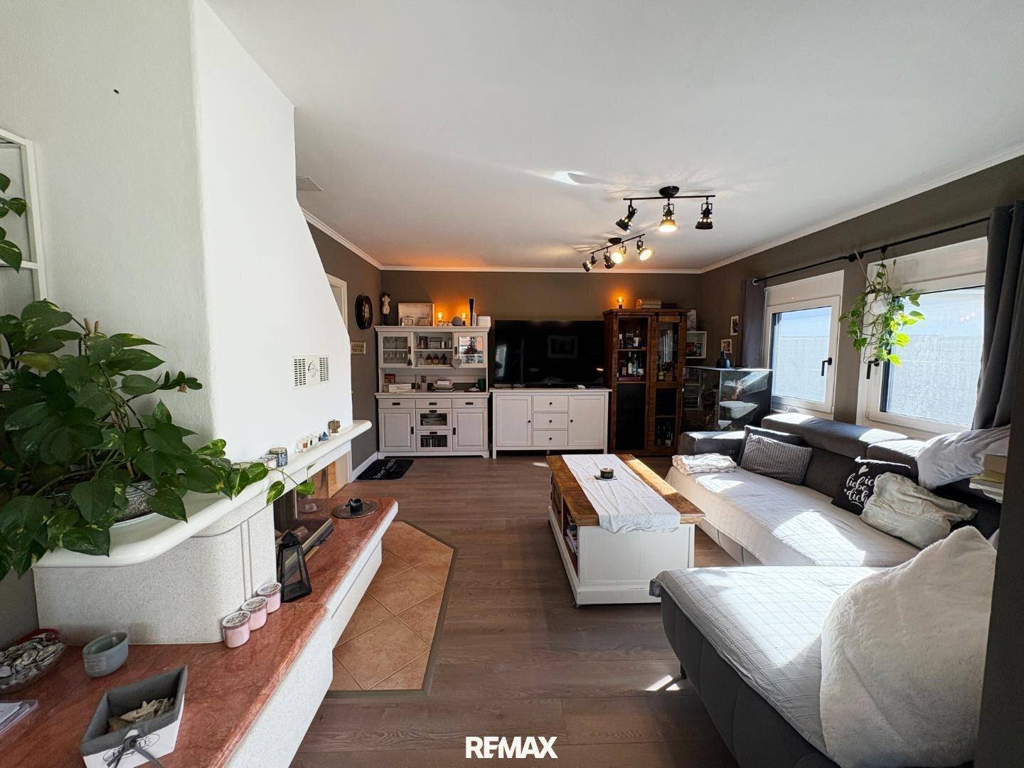 Gemütliches Wohnzimmer mit Kamin, Sofa und Laminatboden, hell und einladend.