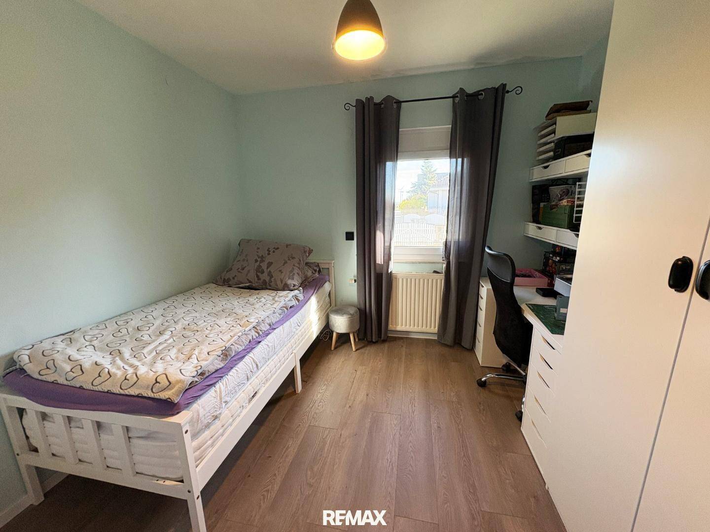 Kinder- oder Gästezimmer mit Einzelbett, Schreibtisch und Laminatboden.