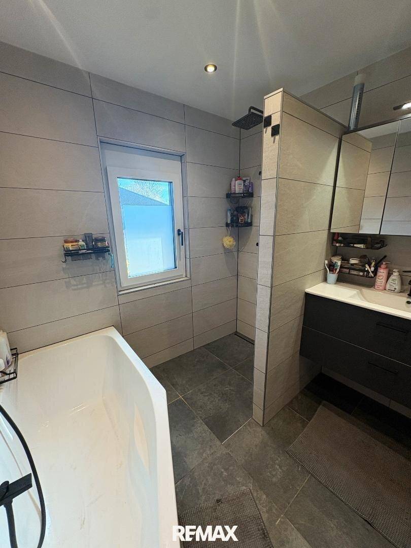 Modernes Badezimmer mit Badewanne, begehbarer Dusche und großformatigen Fliesen.