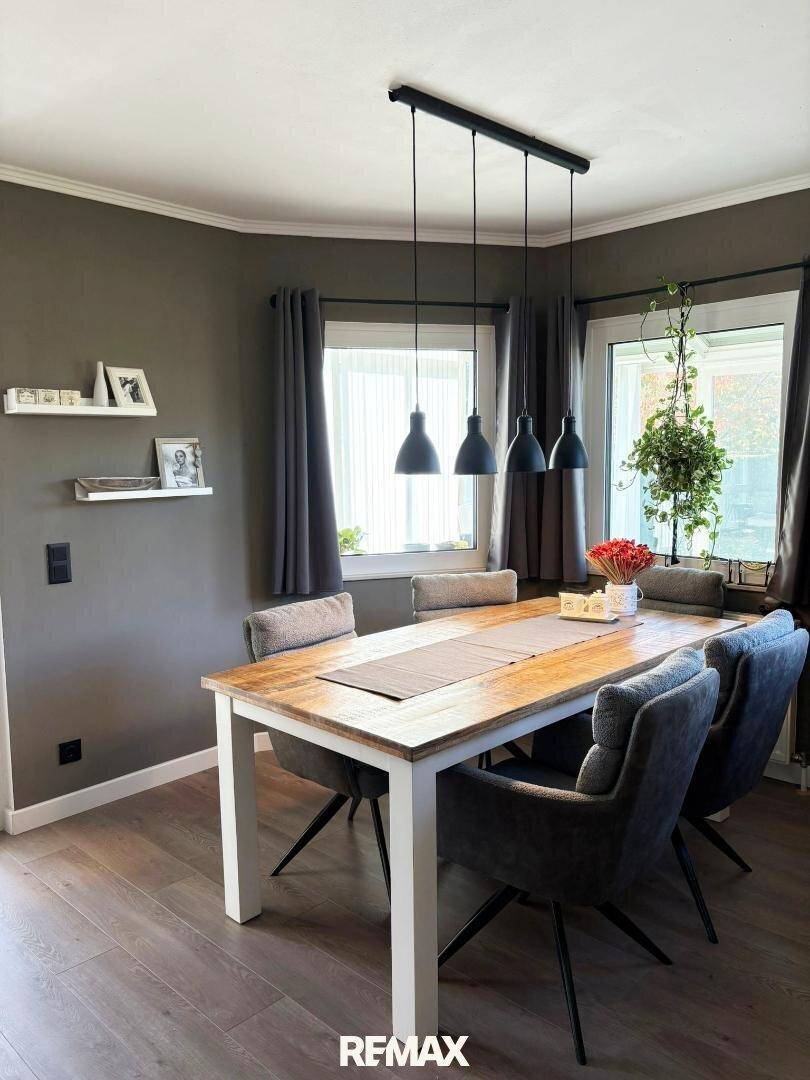 Heller Essbereich mit Holztisch, modernen Stühlen und Laminatboden.