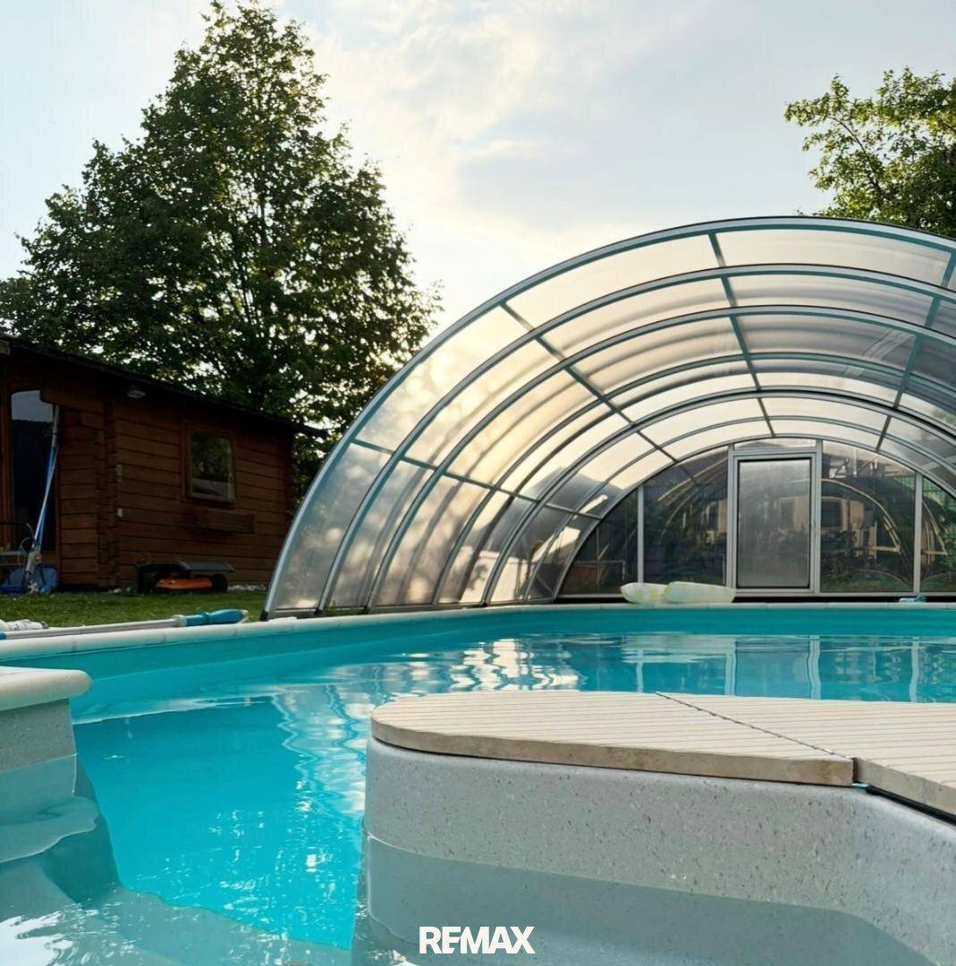 Überdachter Swimmingpool im Gartenbereich, ideal für ganzjährigen Badespaß.