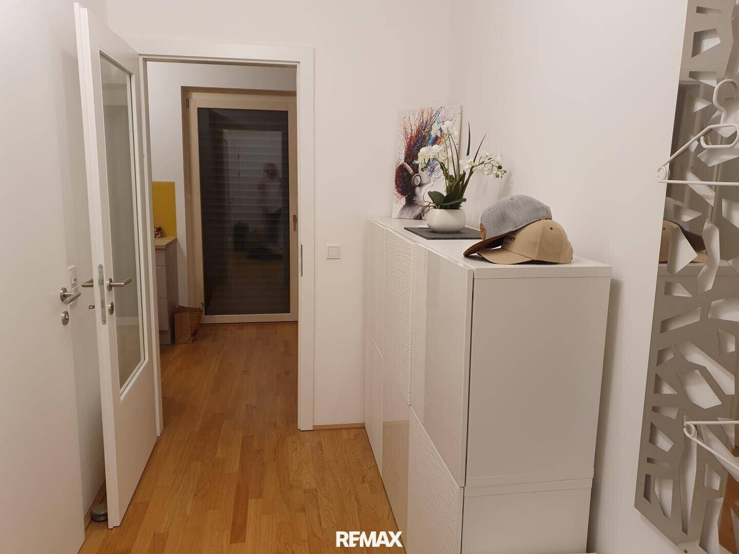 Heller Flur mit Parkettboden und praktischem Schuhschrank, der zu weiteren Räumen führt.