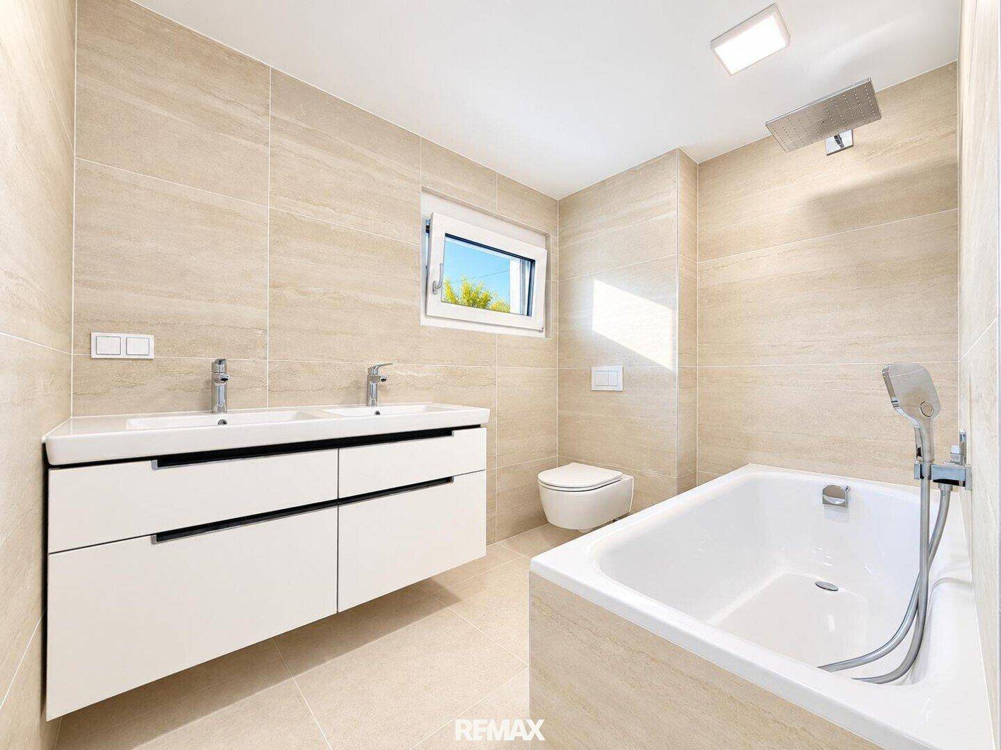 Elegantes Badezimmer mit Doppelwaschbecken, Badewanne und Dusche, in hellen Naturtönen.