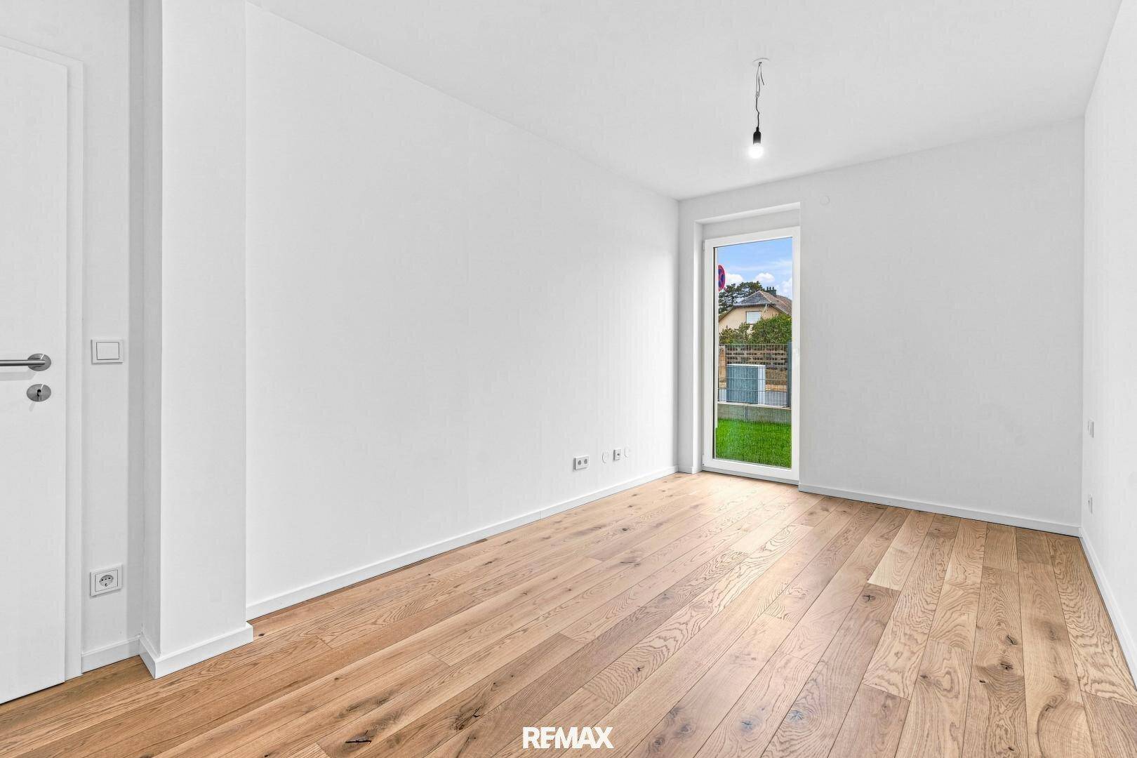 Heller, leerer Raum mit weiß gestrichenen Wänden und hochwertigem Holzfußboden.