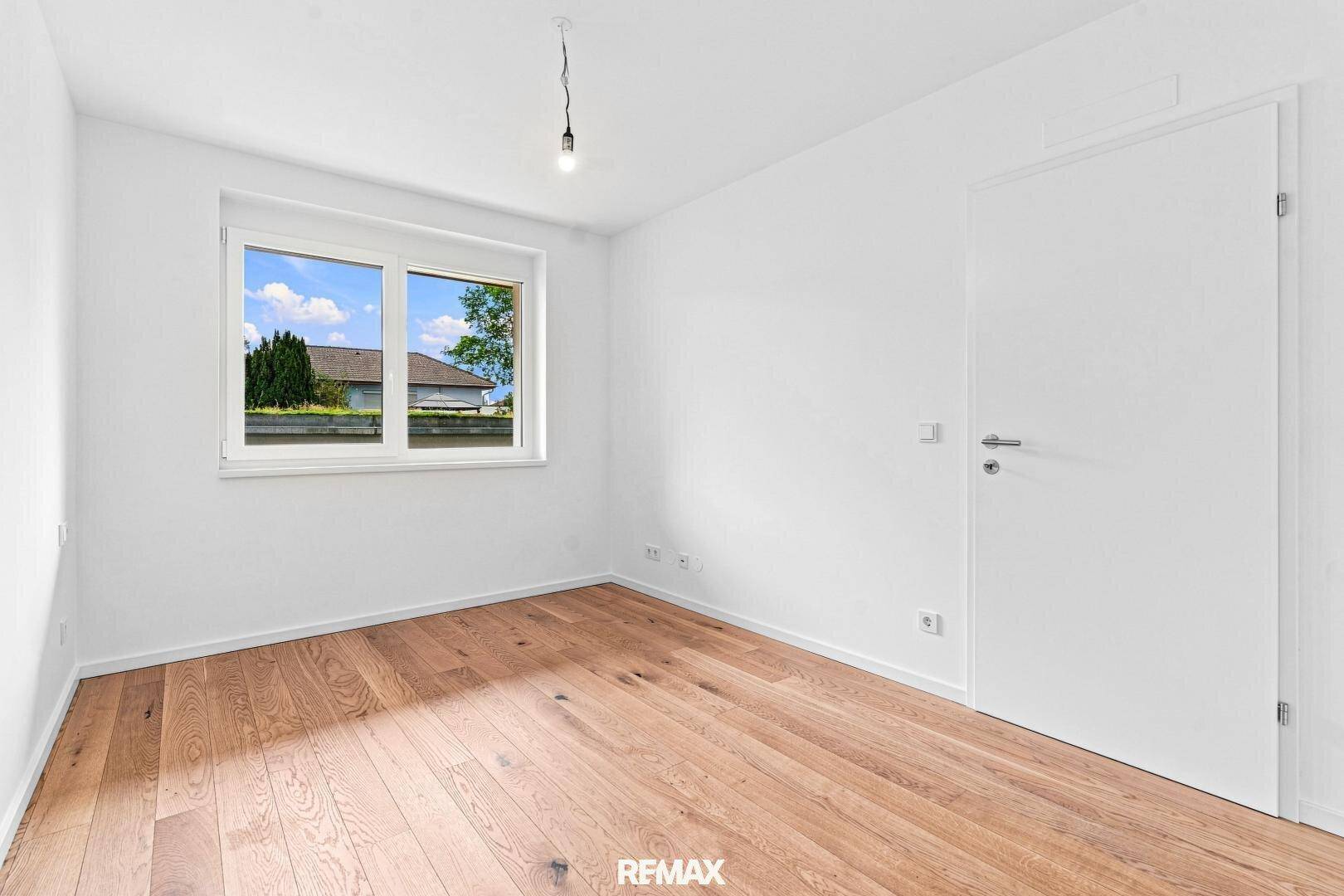 Helles, leeres Zimmer mit Holzboden und Fenster, ideal als Schlafzimmer oder Büro.