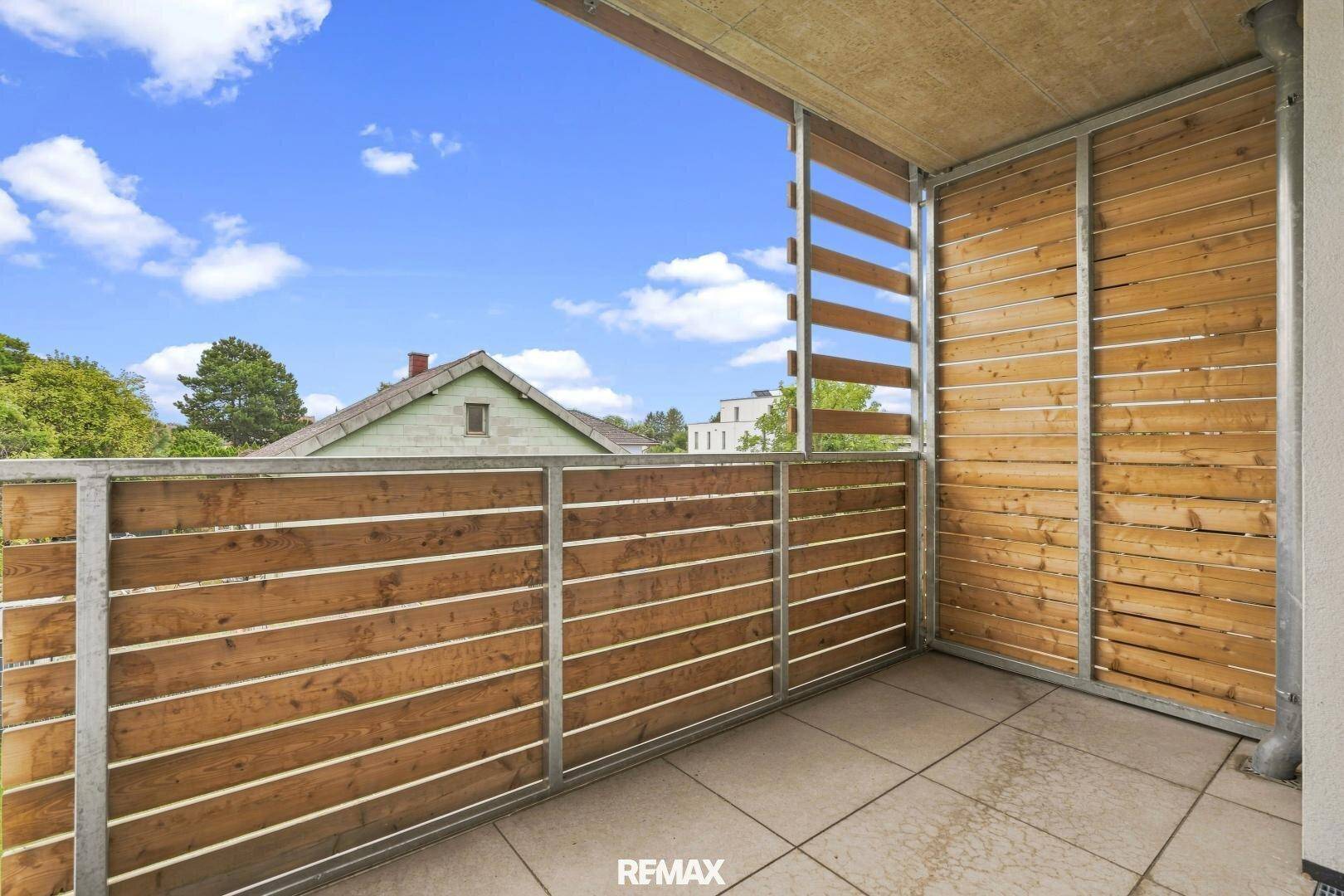 Geräumiger Balkon mit Holzverkleidung und Blick auf die umliegende Wohngegend.