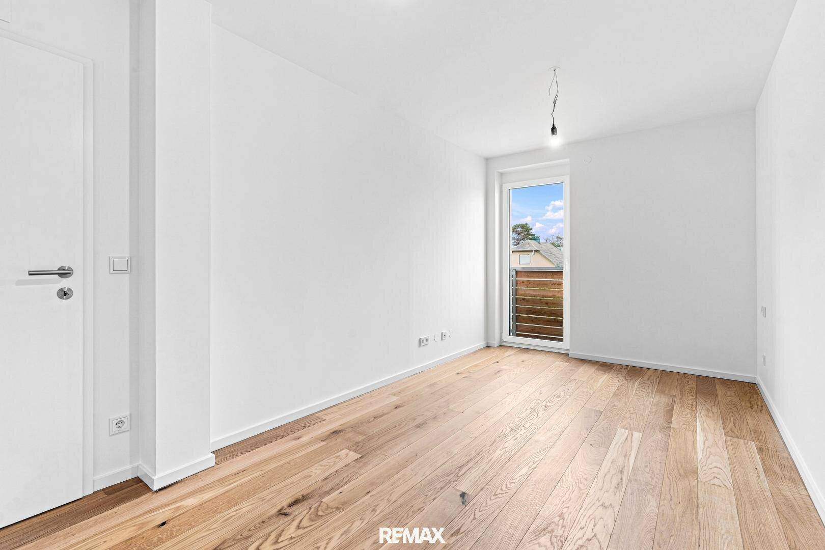 Leeres Zimmer mit Holzboden und Fenster, ideal als Schlaf- oder Arbeitszimmer.