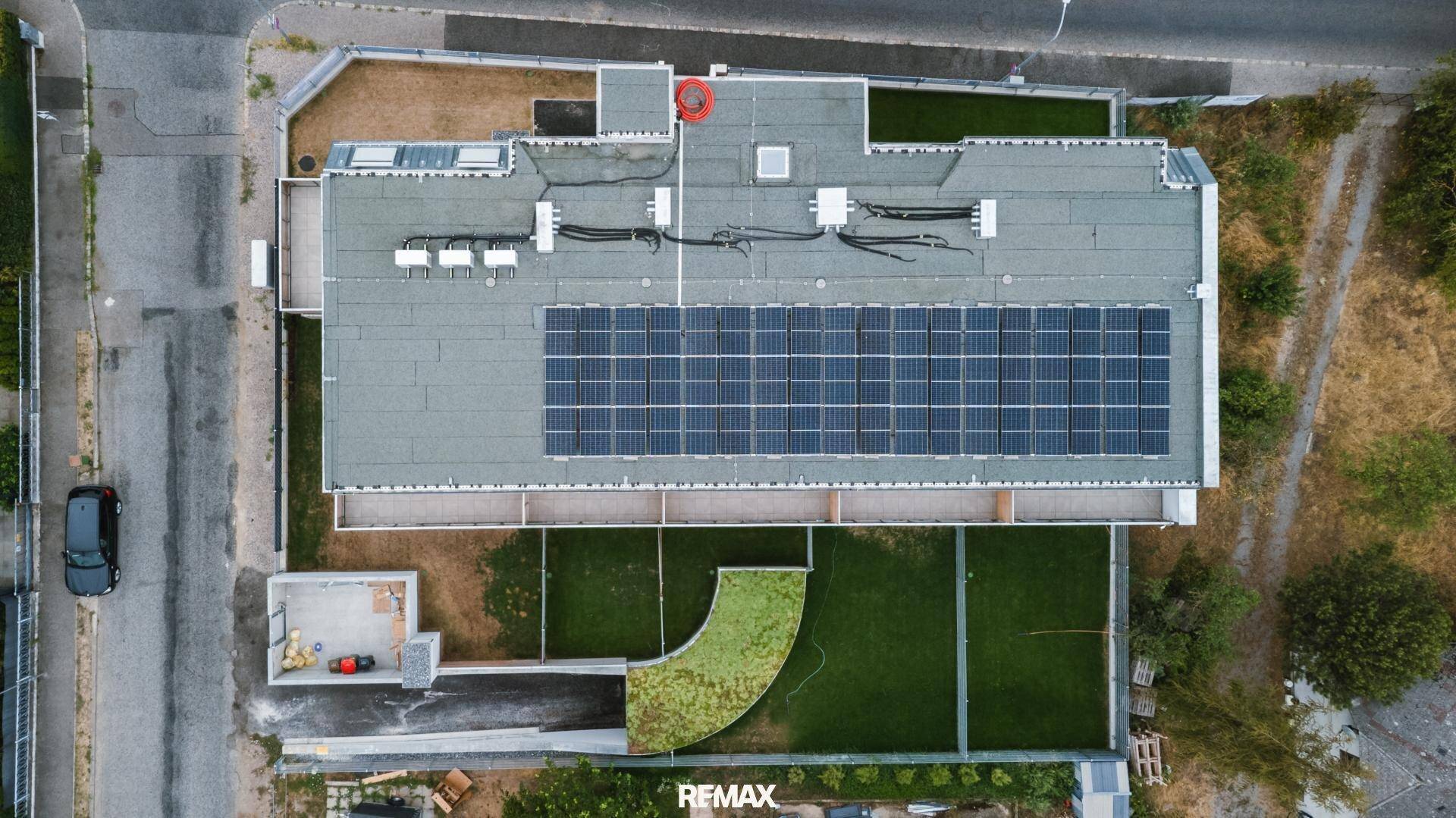 Senkrechte Luftaufnahme des Gebäudes mit Photovoltaikanlage auf dem Flachdach.