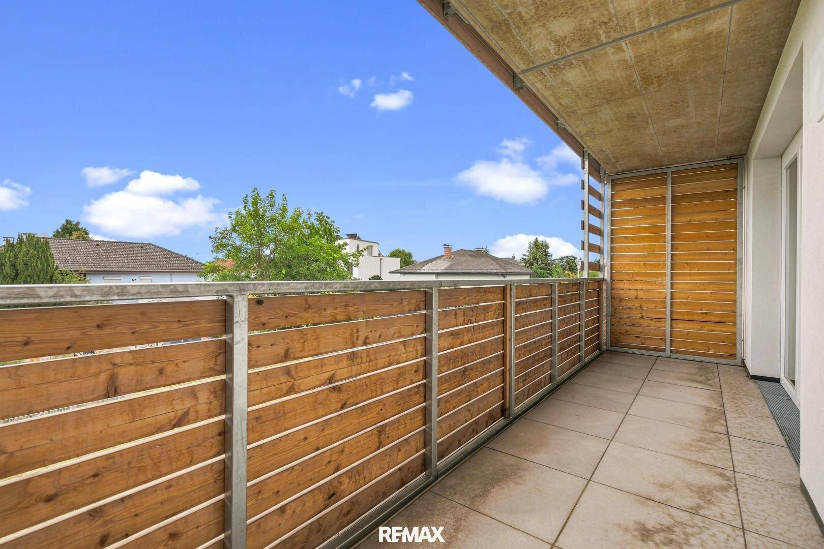 Geräumiger Balkon mit Holzsichtschutz und Fliesenboden, ideal zum Entspannen im Freien.