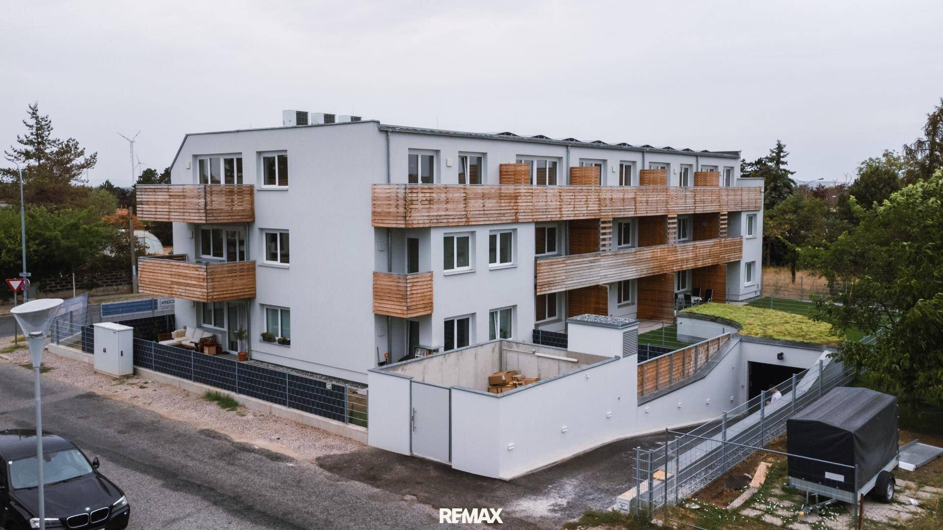Moderne Wohnanlage mit Holzverkleidung an den Balkonen und gepflegten Außenanlagen.