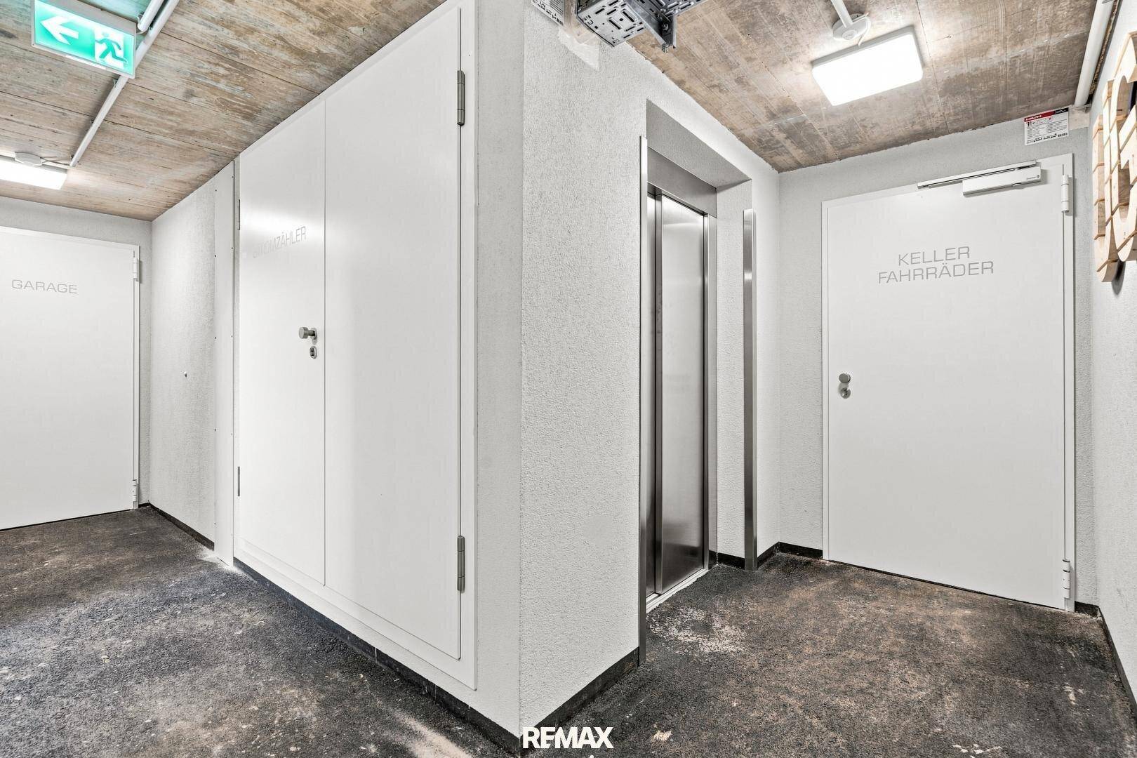 Heller Flur im Untergeschoss mit Zugang zu Keller, Fahrradraum und einem modernen Aufzug.