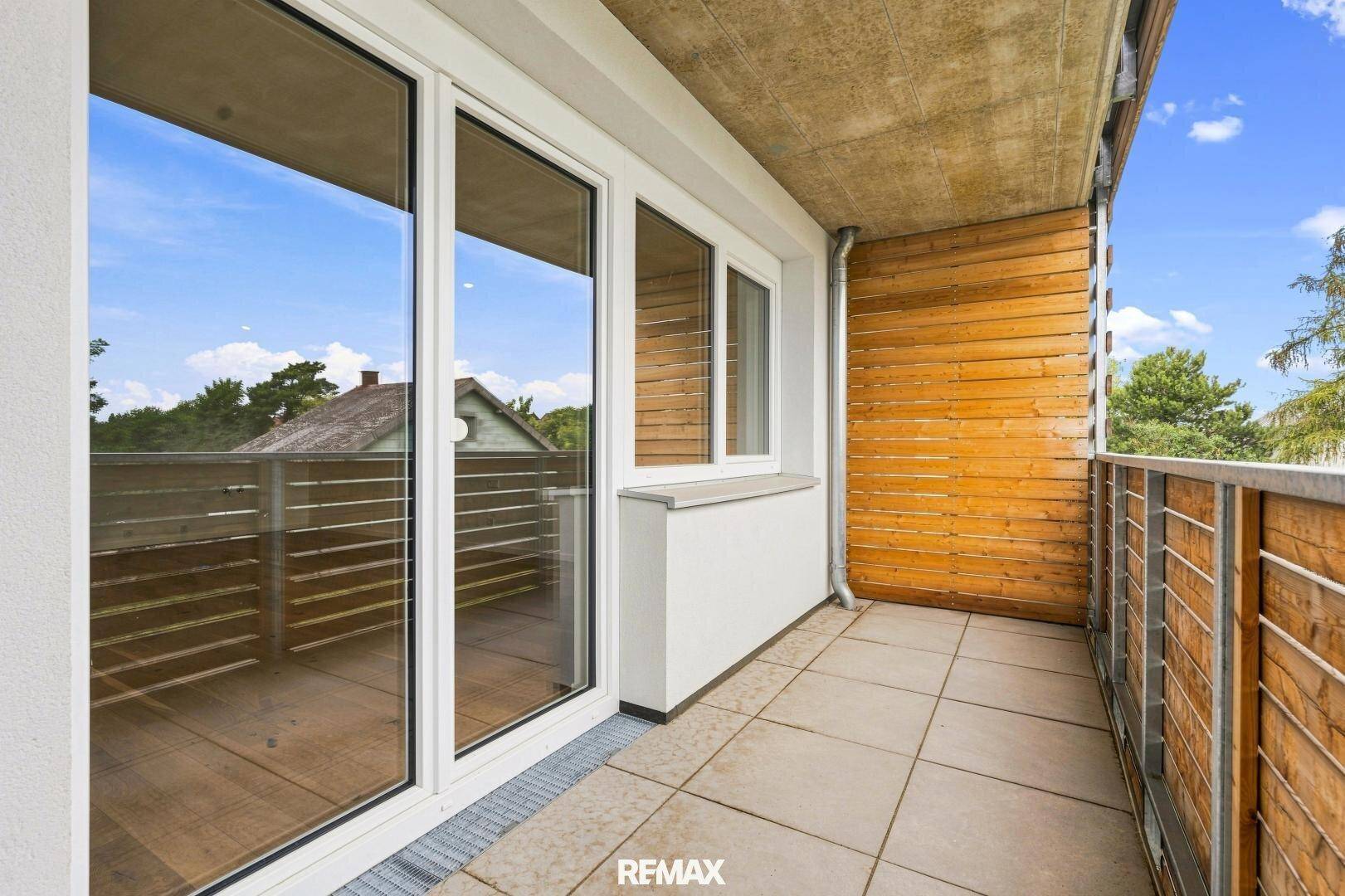 Moderner Balkon mit Fliesenboden und Holzverkleidung, bietet einen angenehmen Außenbereich.