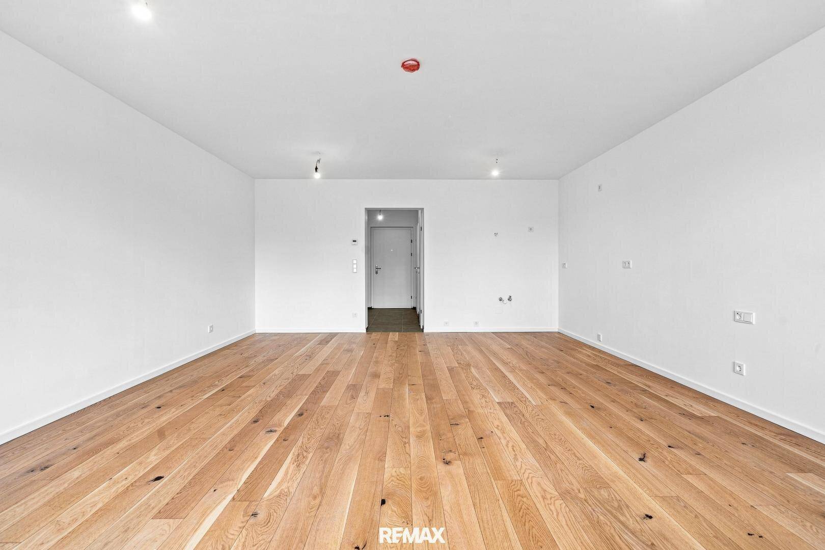 Leerer Wohnraum mit Holzboden und einer modernen Innentür, bereit zur individuellen Gestaltung.